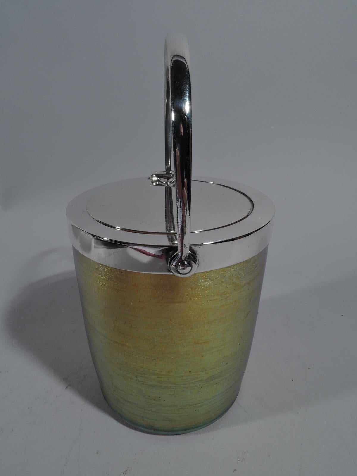 Beautiful Art Nouveau sterling silver and Favrile glass jam pot. Made by Tiffany & Co. in New York. Cylindrical with straight sides. Glass nuanced and striated gold. Pontil mark. Silver collar with flush hinged cover that opens by lowering the