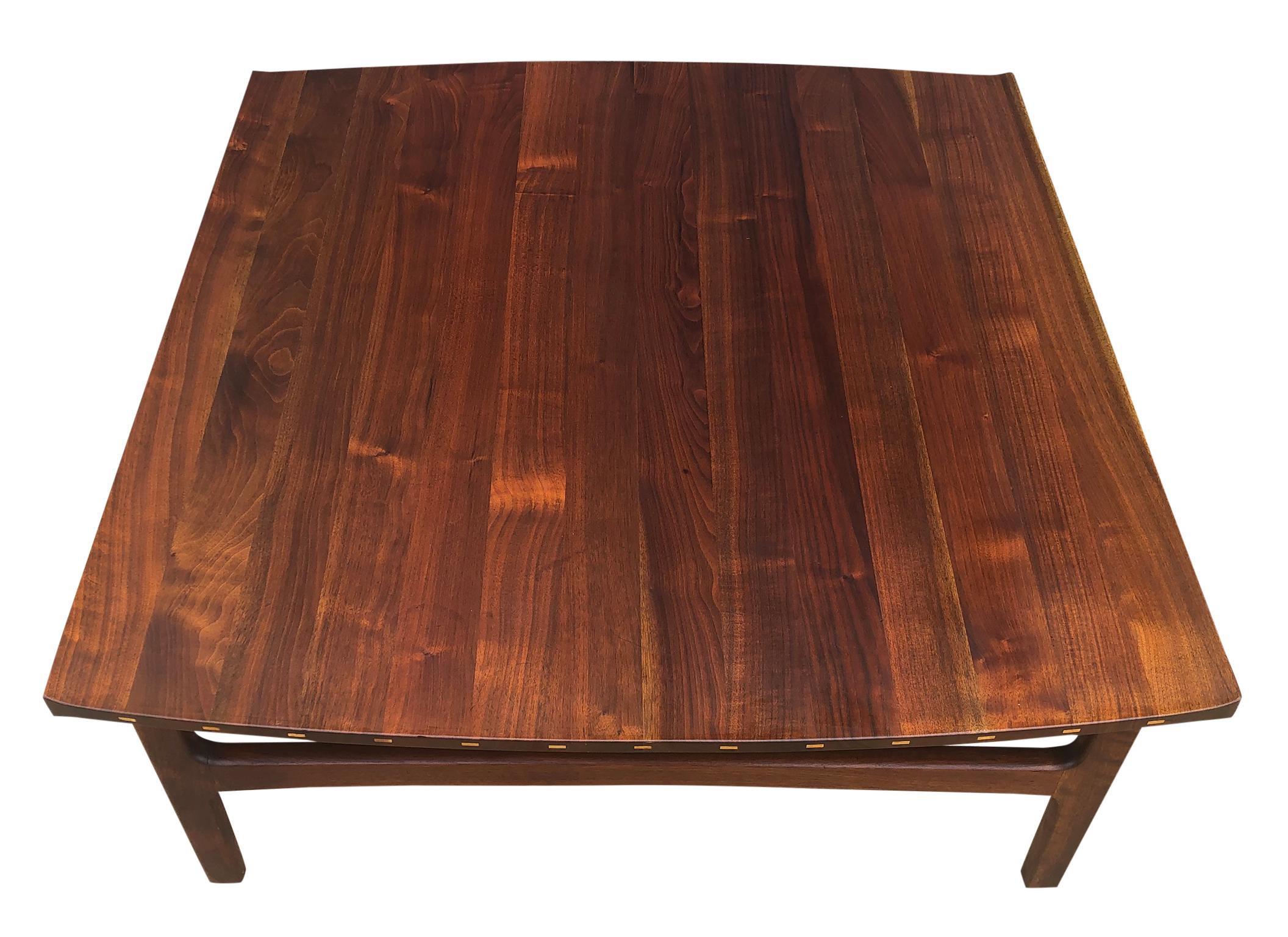 Stunning detailed solid teak Swedish coffee table featuring sculptural lipped edge top with two elegantly curved sides. Exposed wood joinery on the curved edges feature distinctive inlays in lighter, contrasting wood. Exceptional vintage condition