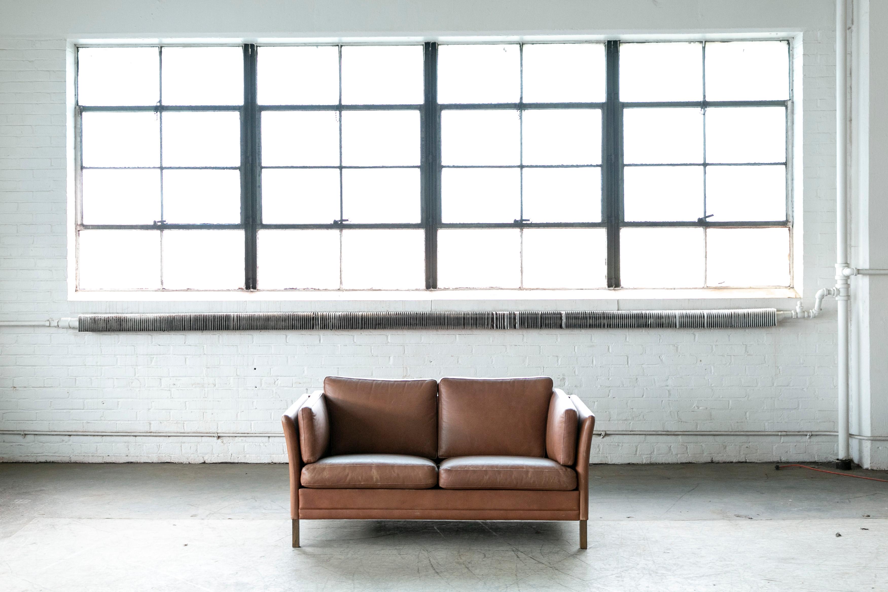 A beautiful Danish cognac colored two-seat sofa designed and manufactured by Mogens Hansen sometime in the 1970's This 