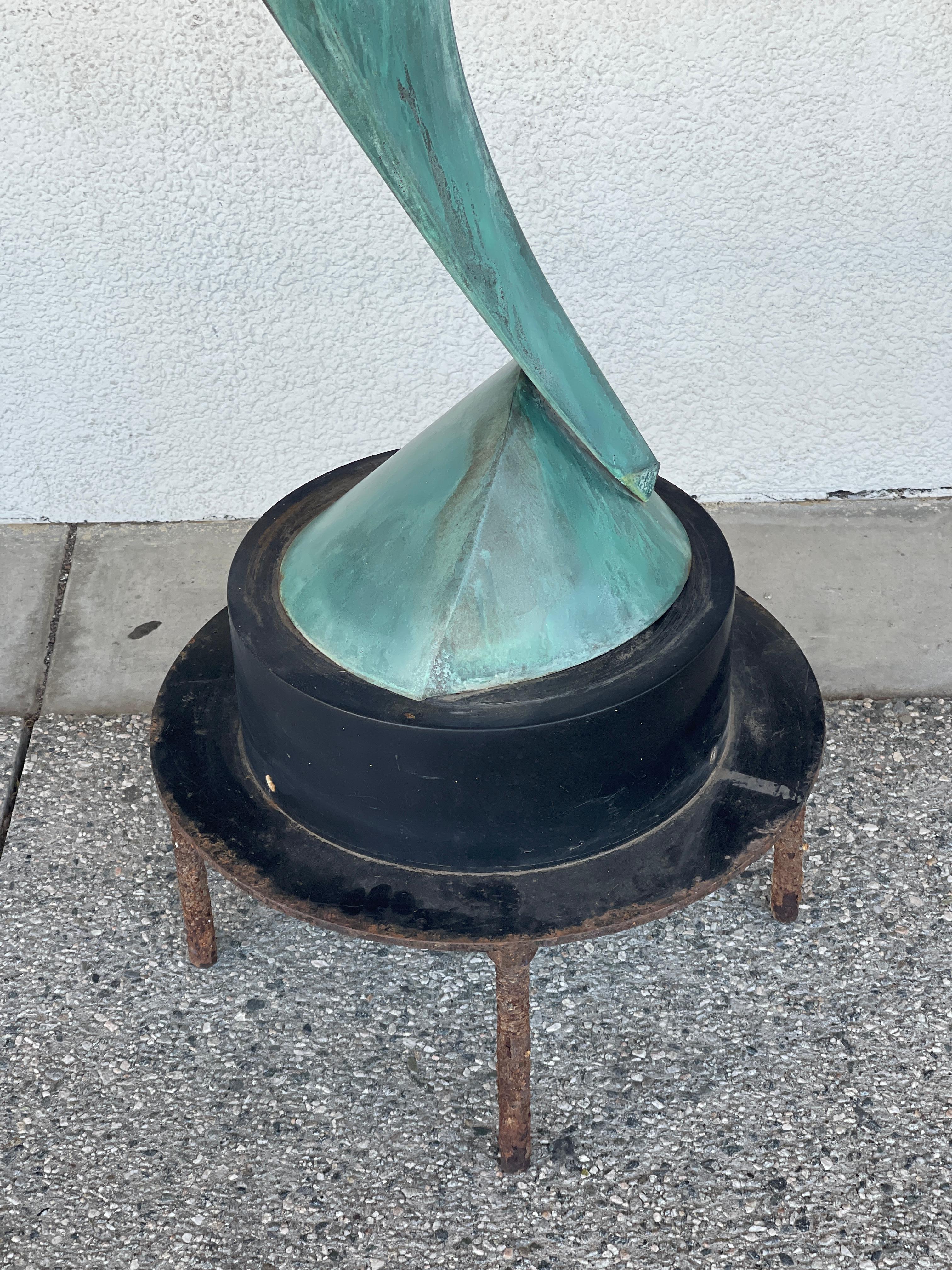 Beautiful aged verdigris patina copper sculpture titled “Undeciphered Oracle” by the noted artist Lyle London. It is from 1998. It is accompanied with a copy of a certificate of authenticity from the artist. It is mounted on an iron base with red