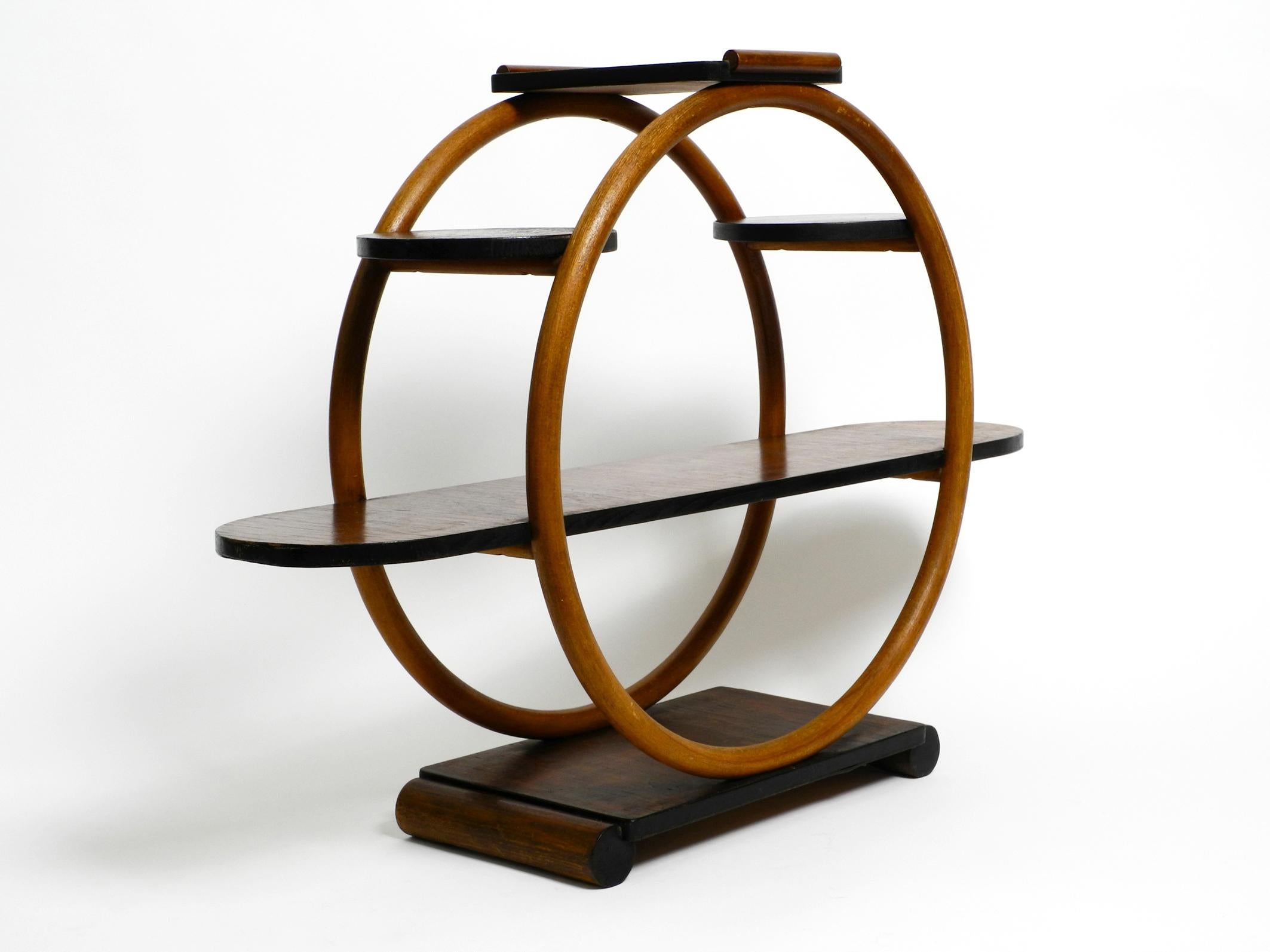 Beautiful very rare Italian Art Deco mid-century wooden shelf or plant stand.
Very unusual design Made in Italy. Probably from the 1930s.
The lateral round frames are made of bentwood.
The surfaces are made of wood with dark walnut veneer. The