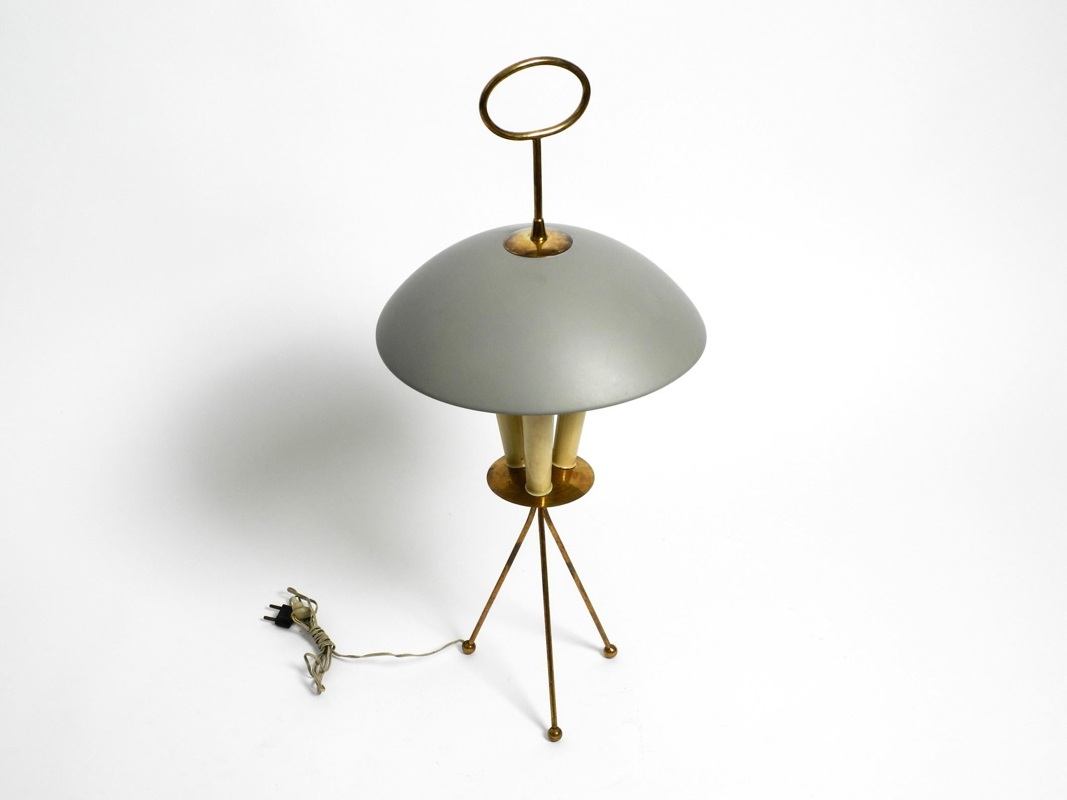 Beautiful very rare large Italian mid century tripod table lamp or floor lamp.
Frame and handle at the top are made of brass, the socket cones are made of plastic and the shade is made of metal.
Typical classic mid century design from Italy in