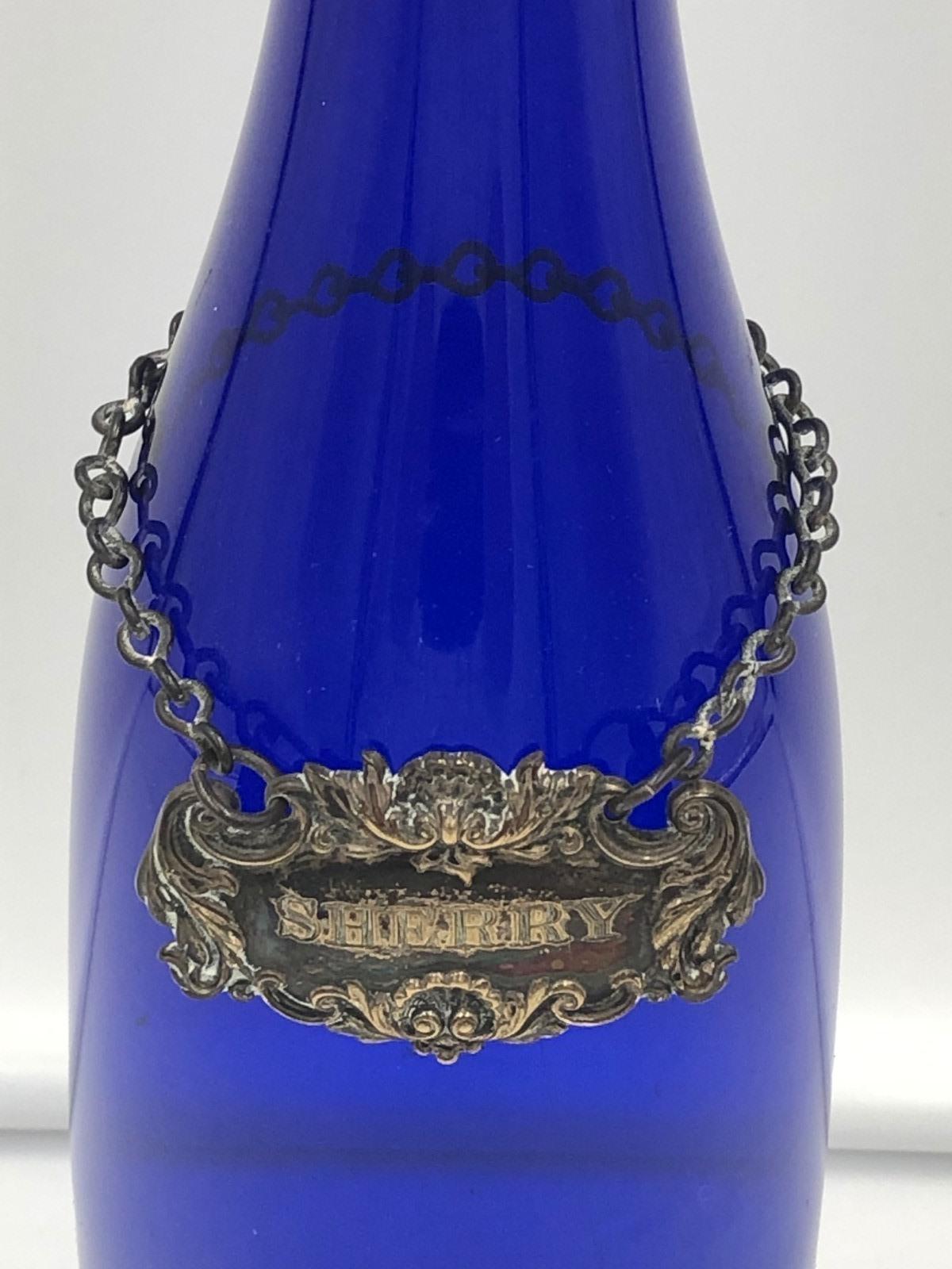 Schöne viktorianische Blauglas-Weinflasche mit silbernem Hals, der vergoldete fruchtige Rebenstopfen über dem silbernen fruchtigen Rebenhals mit versilbertem Dekanter-Sherry Label.

Punzierungen Birmingham 1854
Schöpfer:- James Collins