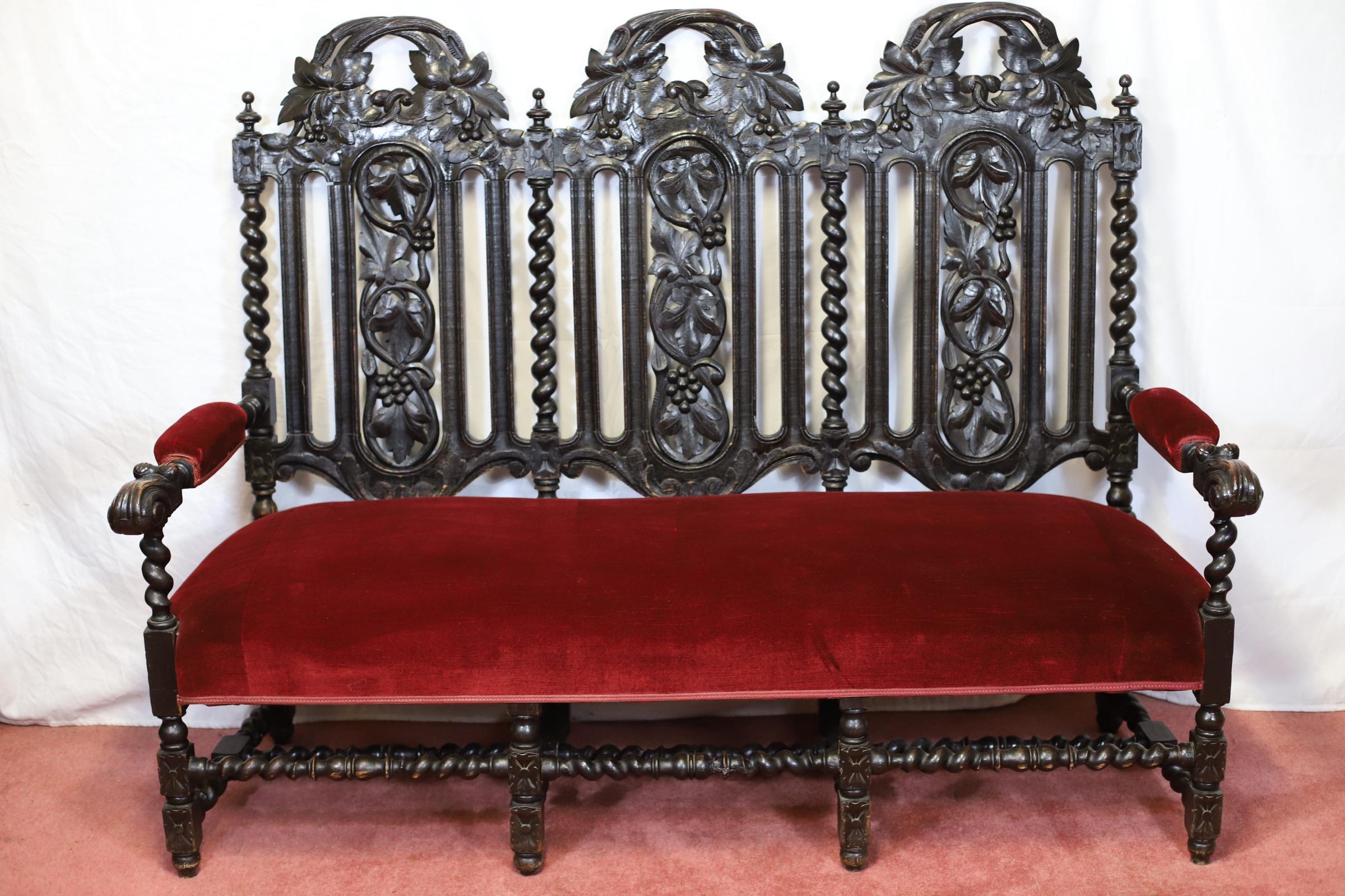We delight to offer for sale this stunning late 19th century Victorian carved oak two-seater settee in Jacobean taste , having elaborate carved back rests with grapes and leaf worked detailing flanked by barley twist supports . Red valour padded