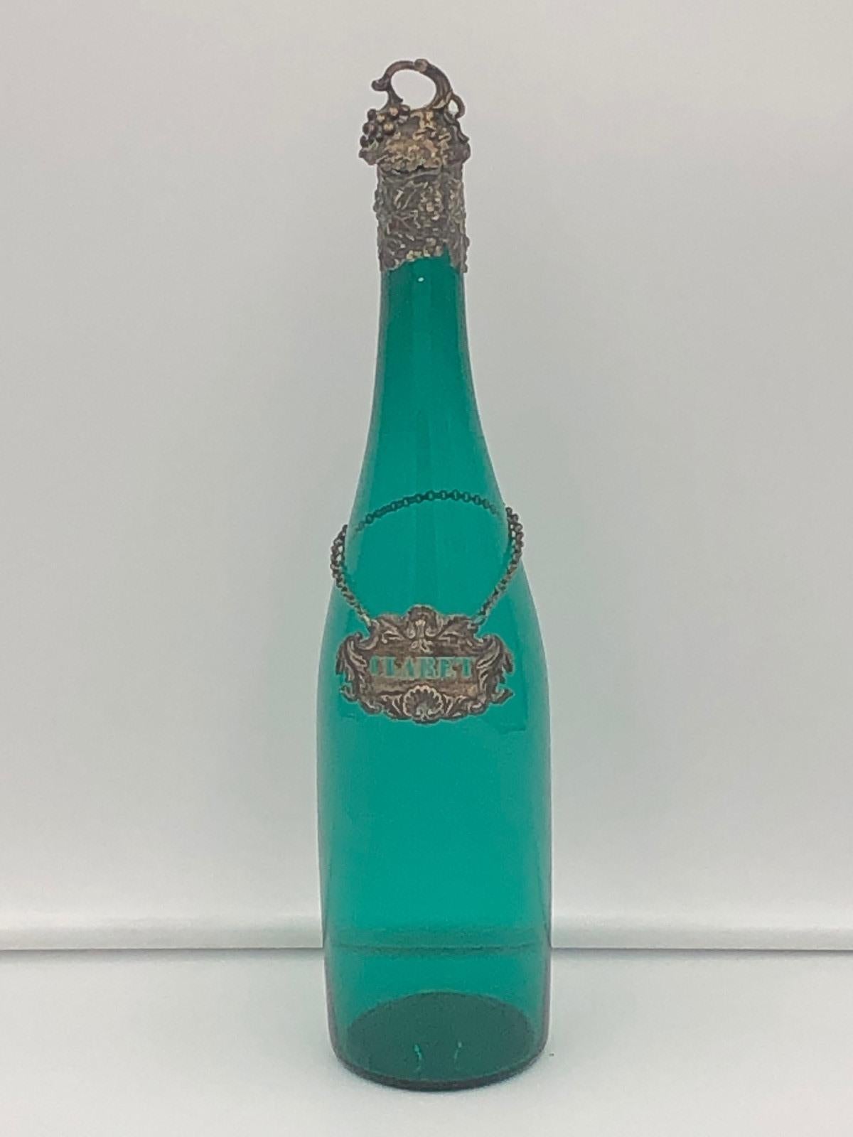 Belle bouteille de vin victorienne en verre vert avec col en argent, le bouchon plaqué de vigne fruitière au-dessus du col de vigne fruitière en argent avec l'étiquette de carafe à bordeaux plaquée argent. 

Poinçons Birmingham 1854
Créateur:- James