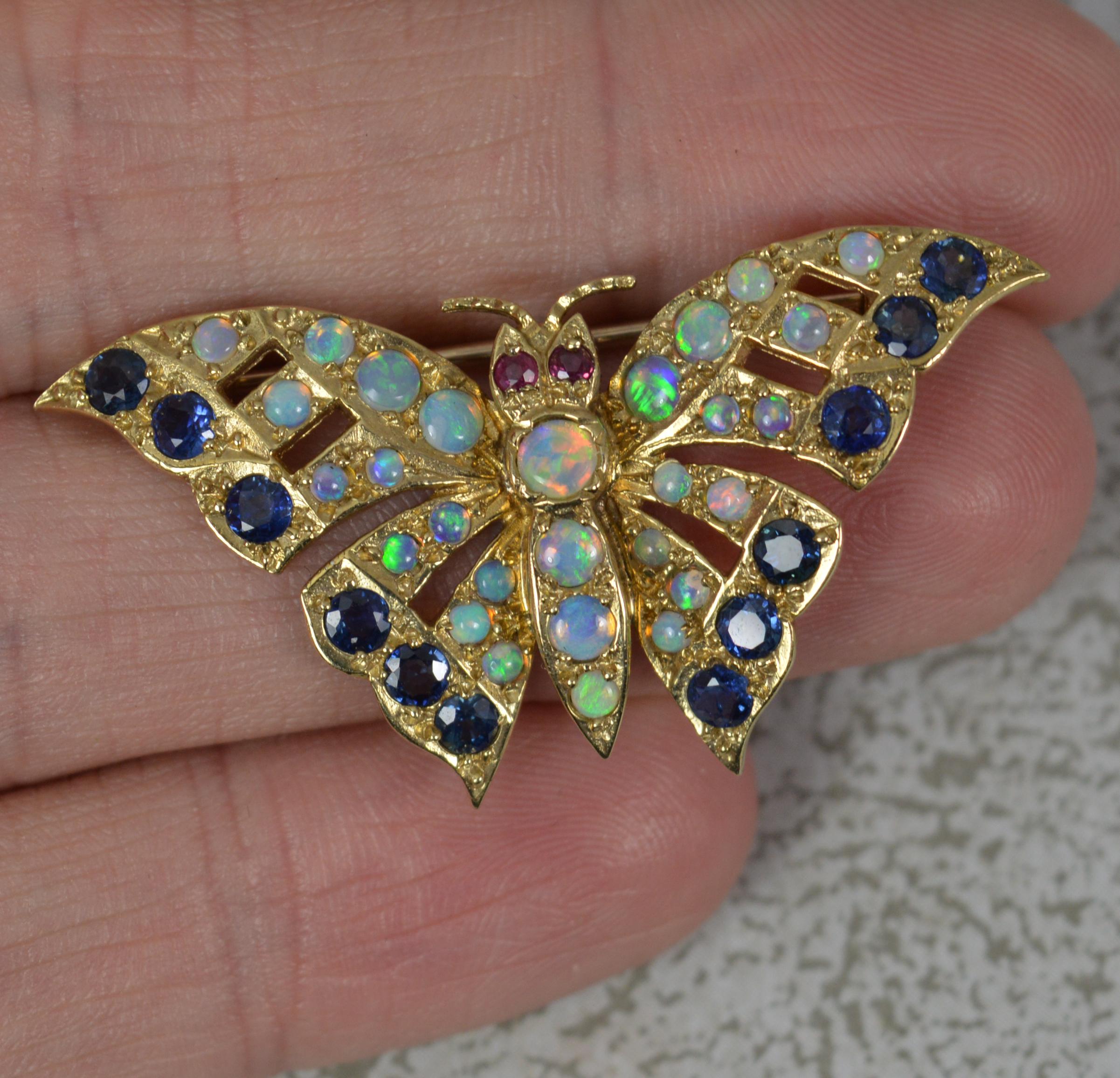 A very fine contemporary brooch of butterfly shape.
Solid 9 carat yellow gold example.
Designed with two natural rubies set to the eyes with many round opals to the body and wings with blue sapphires to the edge.

Condition ; Very good. Working pin
