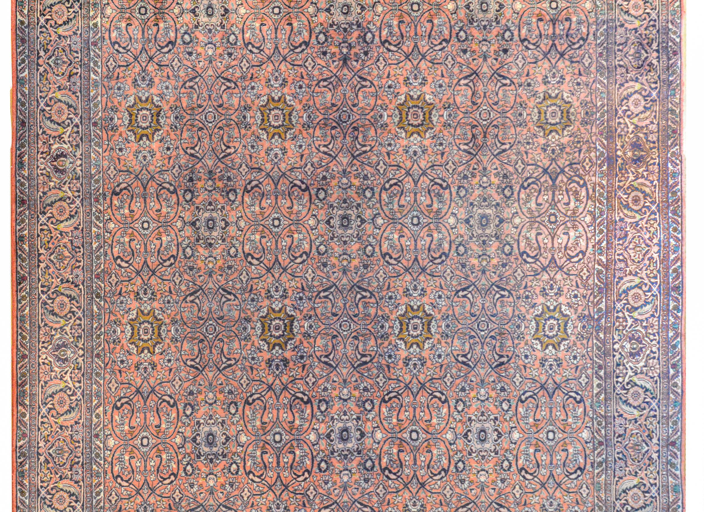 A beautiful vintage Persian Bidjar rug with an all-over trellis floral pattern with scrolling vines and large gold flowers woven in light and dark indigo, pink, and turquoise, against a salmon colored background. The border is wonderful with a