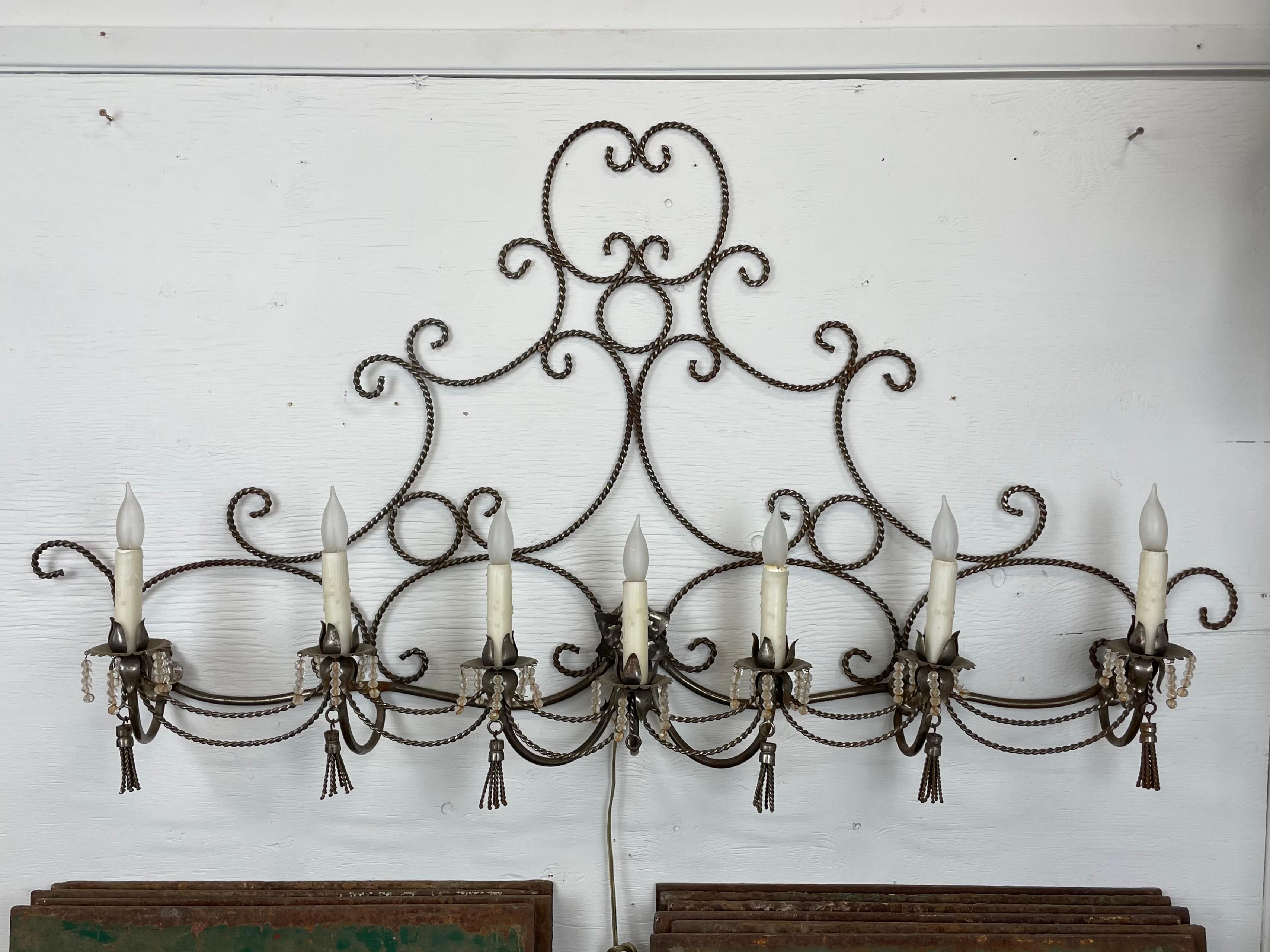 Beautiful unique vintage French wall sconce. What a statement piece and focal point it would make on a wall over a bed or in a bathroom above the sinks. The scrolling rope frame is accented with 6 candle-light bobeches and glass bead drops with