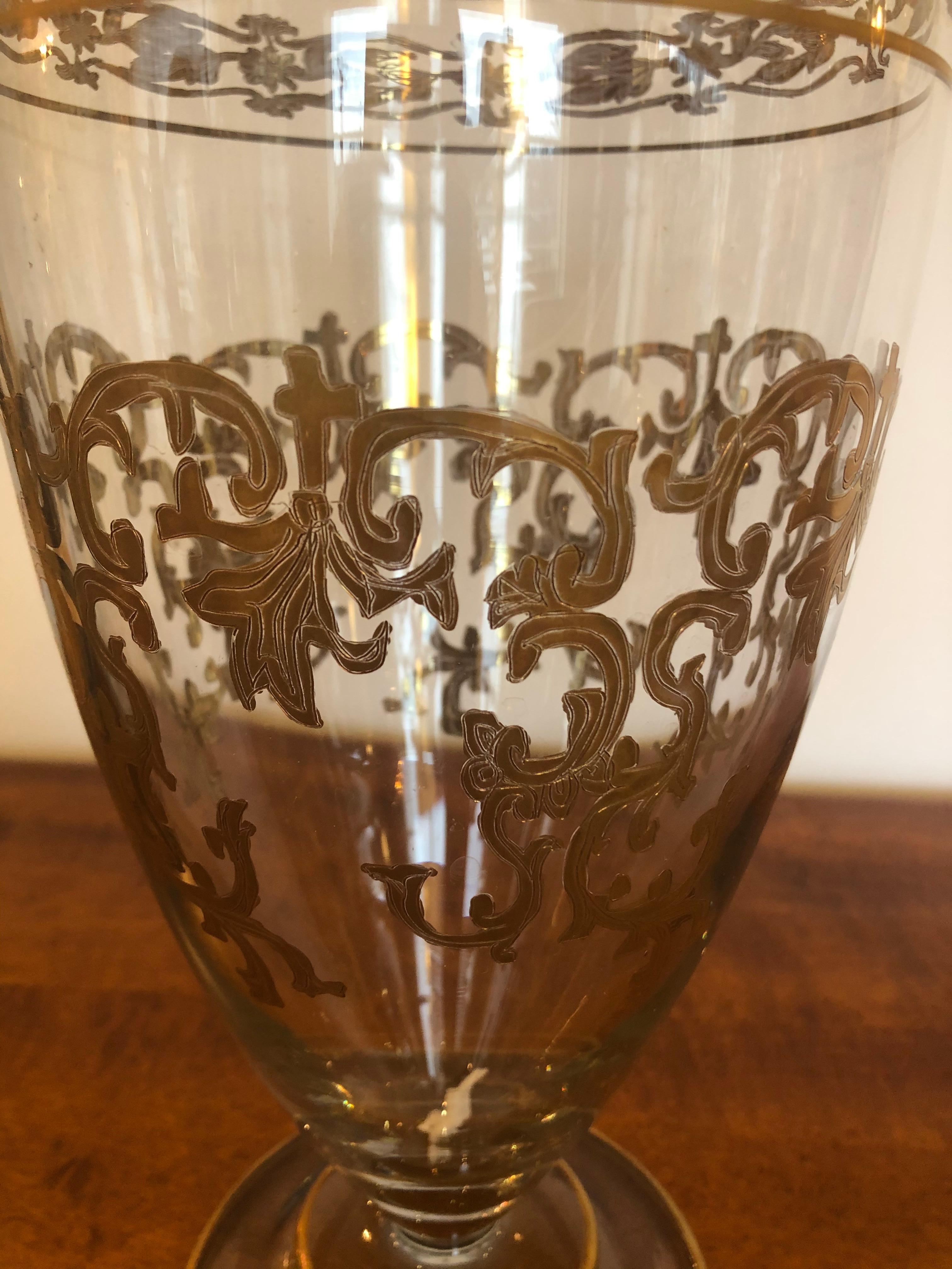 A beautiful medium sized vintage glass vase having ornate gold leaf patterned embellishments.