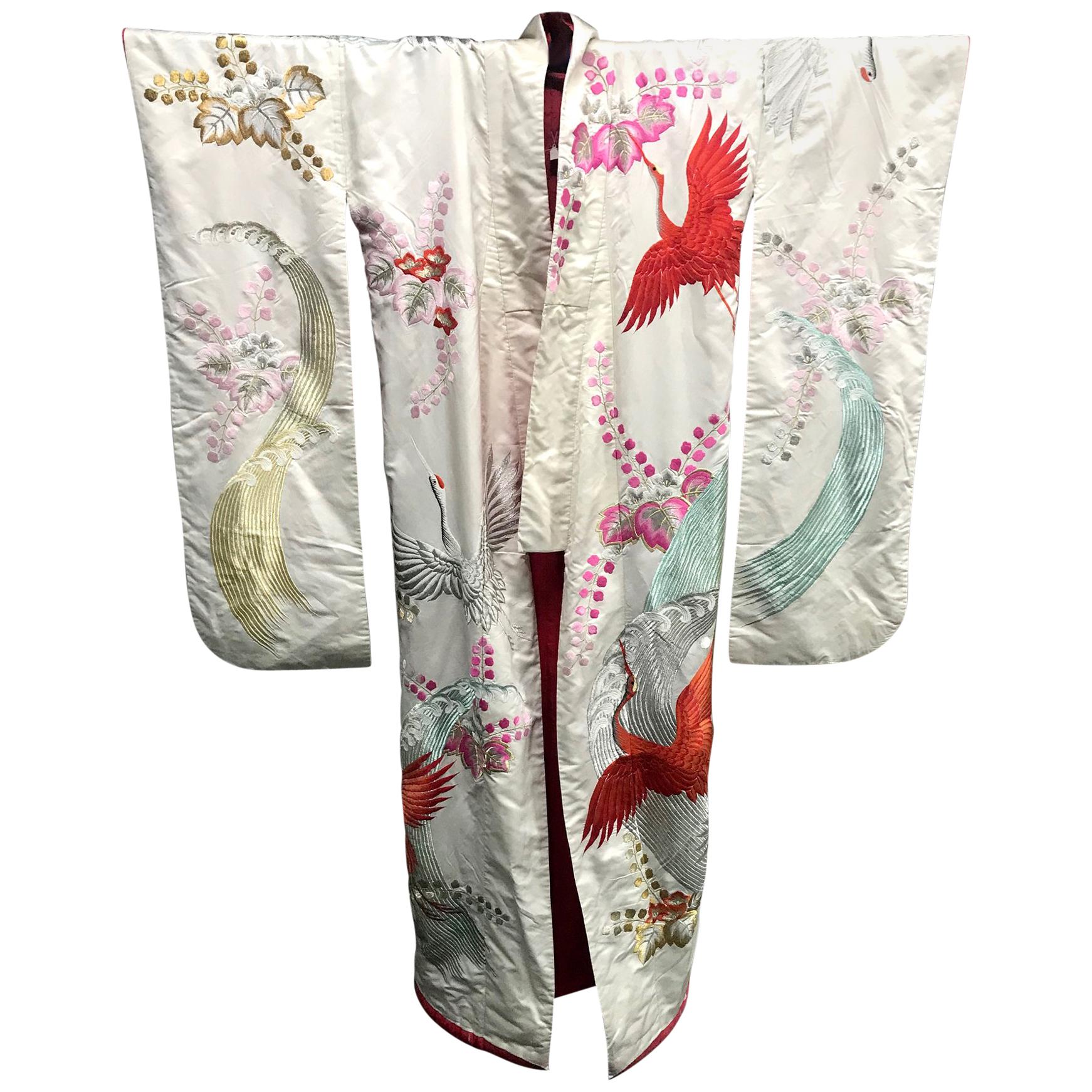 An exceptional Japanese wedding ceremonial kimono Uchitake, circa 1930s in oriental Art Deco fashion. Cream white silk background with elaborate and intricate embroidery in color and gold threads that depict auspicious symbols such as the flying