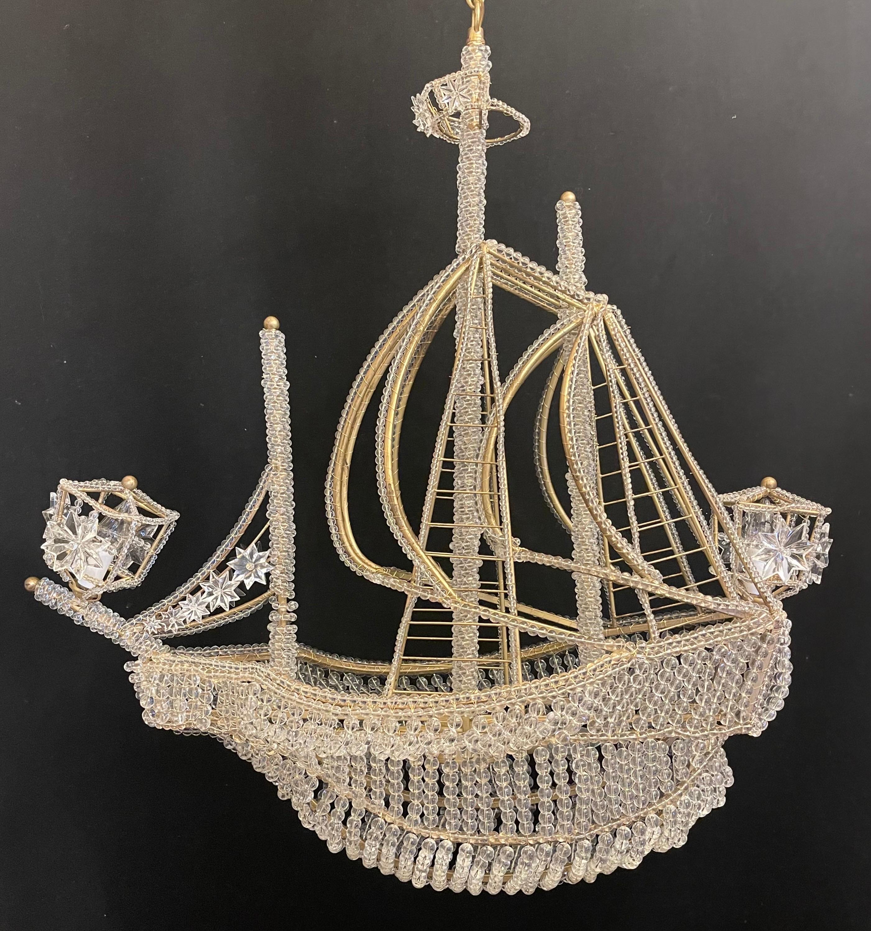 A wonderful boat / ship chandelier that is beautifully detailed with a beaded crystal hull and sails crystal star accents throughout. Outfitted with 4 internal lights two in the main hull and two in the lanterns, In the manner of Baguès.
This would