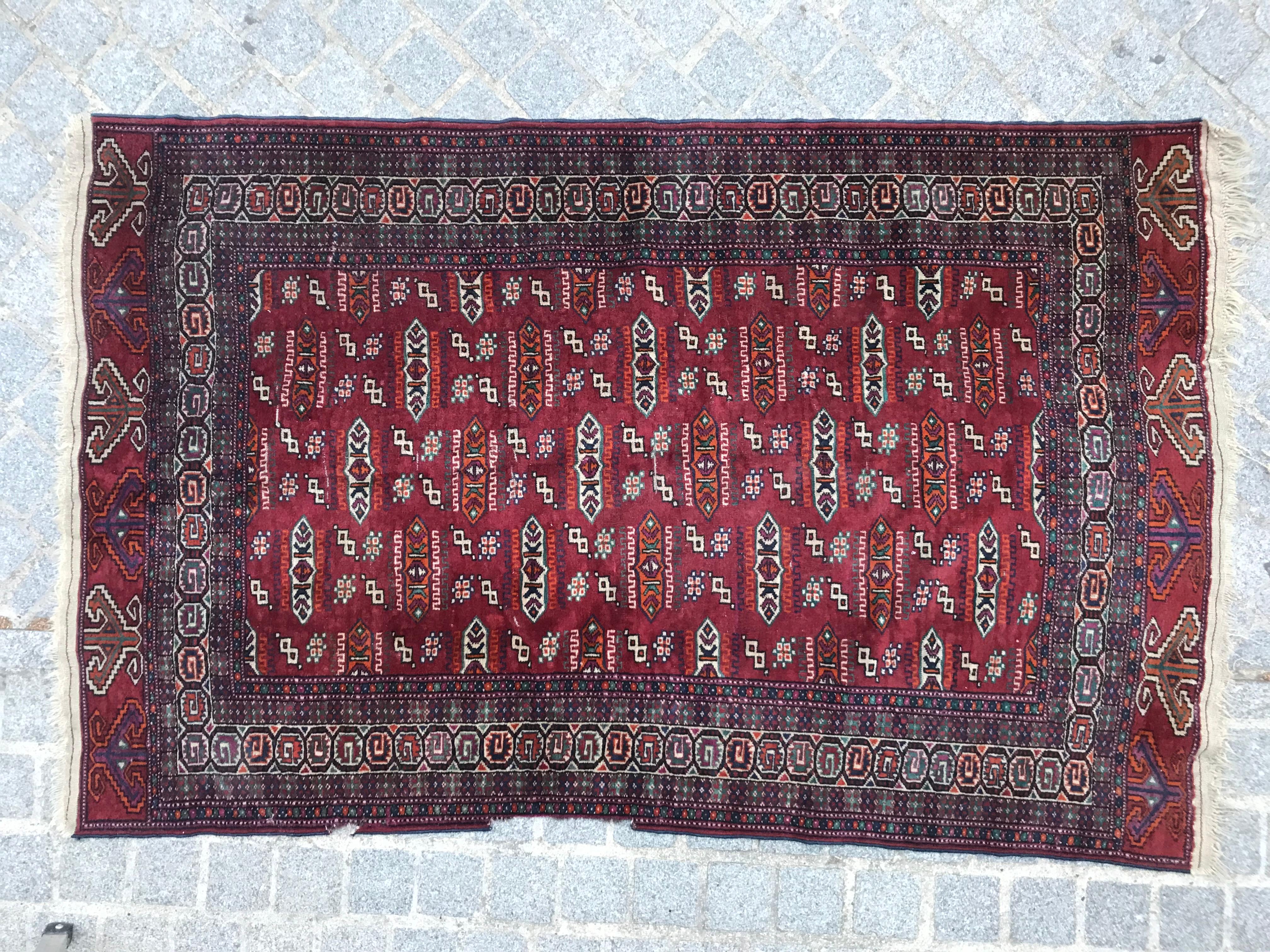 Beautiful late 20th-century Turkmen rug featuring a stunning geometric design and vibrant red field colors. This finely hand-knotted piece is crafted with wool on a wool foundation. The rich red background is adorned with stylized tribal motifs in