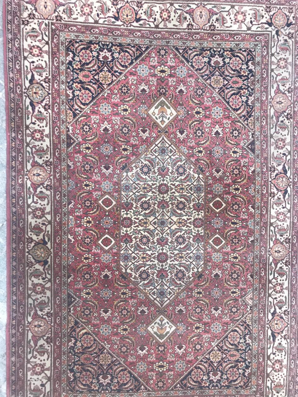 Entdecken Sie die Eleganz dieses exquisiten Teppichs aus dem 20. Jahrhundert mit einem bezaubernden Muster im Tabriz-Stil auf einem schönen rosa Feld, das mit Blau- und Grüntönen verziert ist. Der mit Präzision handgeknüpfte Wollsamt auf