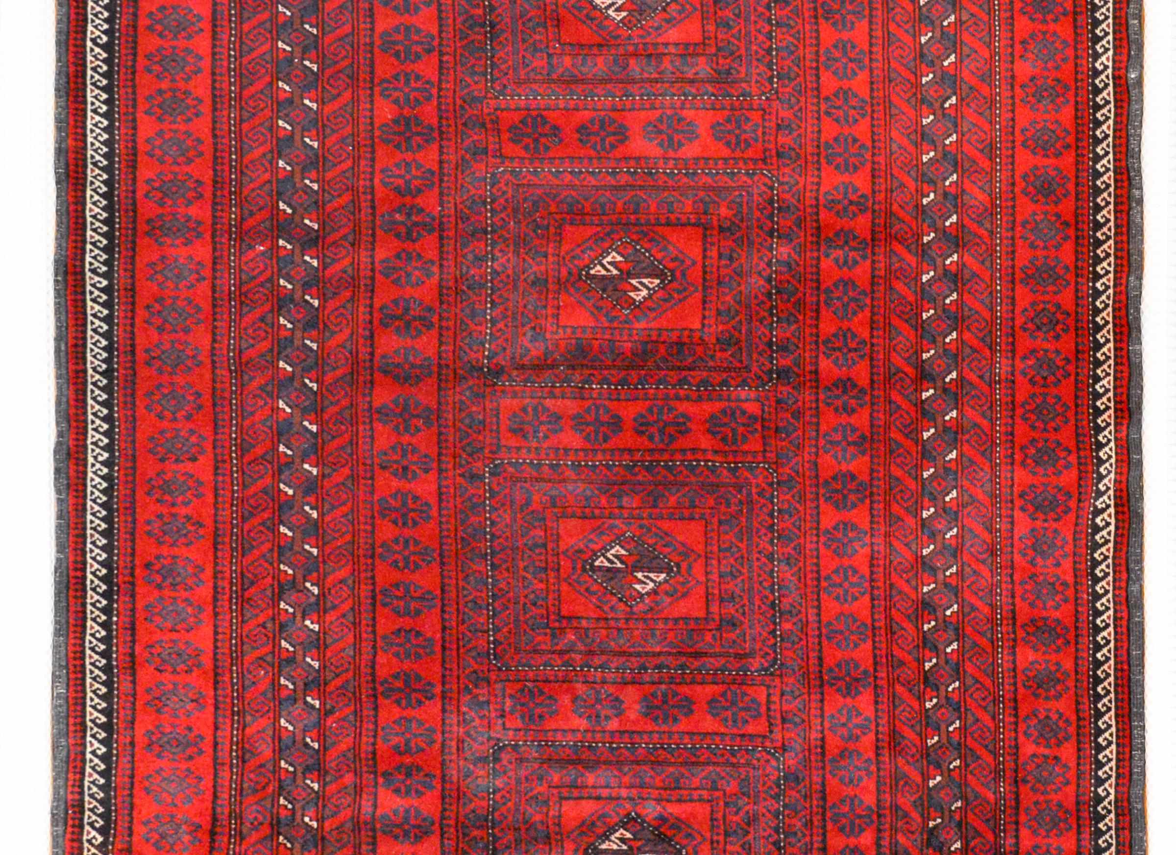 A beautiful mid-20th century Afghani Turkmen rug with six square medallions surrounded by an elaborate and wide border composed of myriad geometric and floral patterned stripes all woven in light and dark indigo, and white vegetable dyed wool