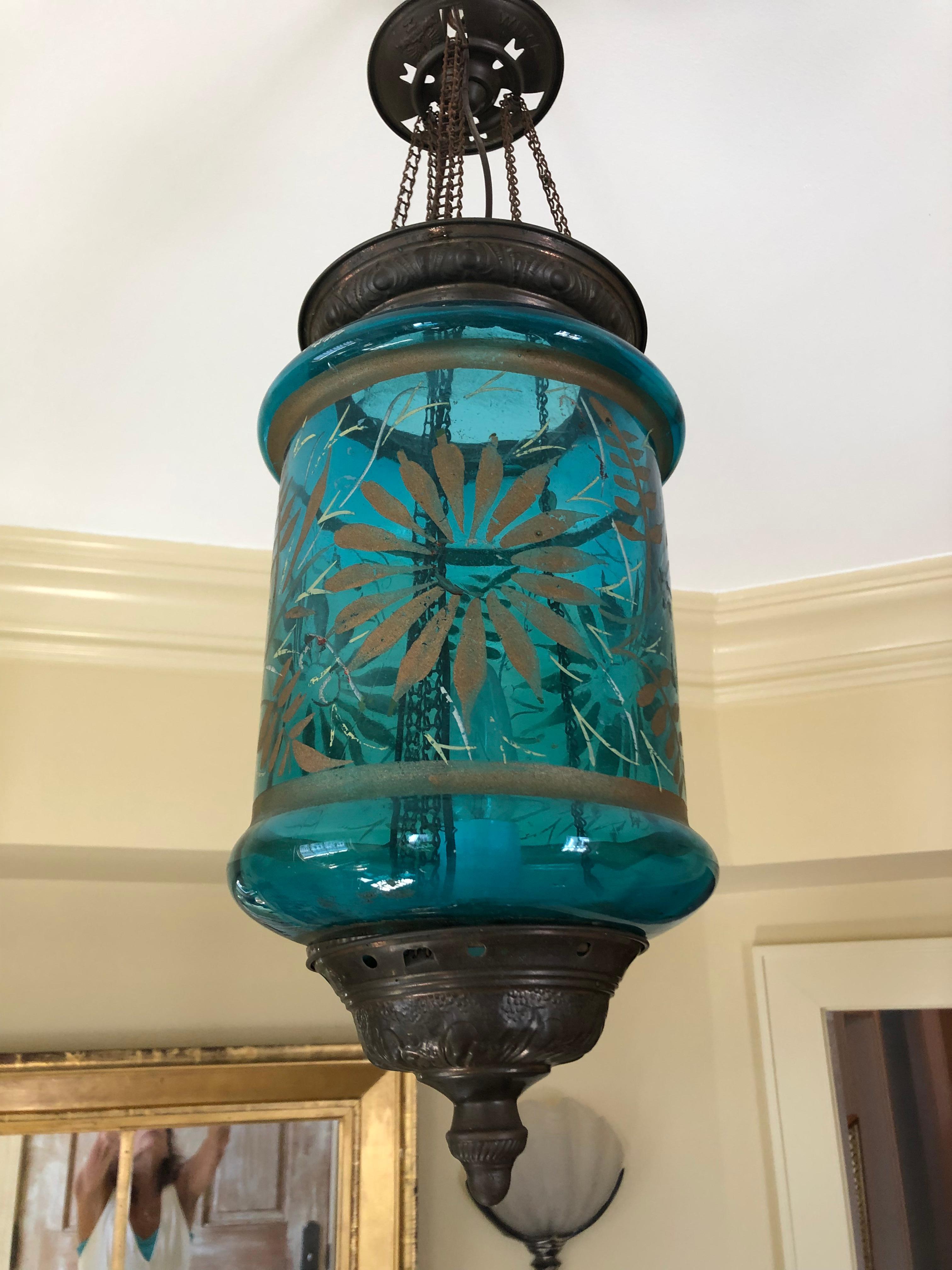 A wonderful antique turquoise glass lantern with floral decoration and bronze colored brass base, top, and original ceiling cap. Makes an eye catching lovely foyer fixture.