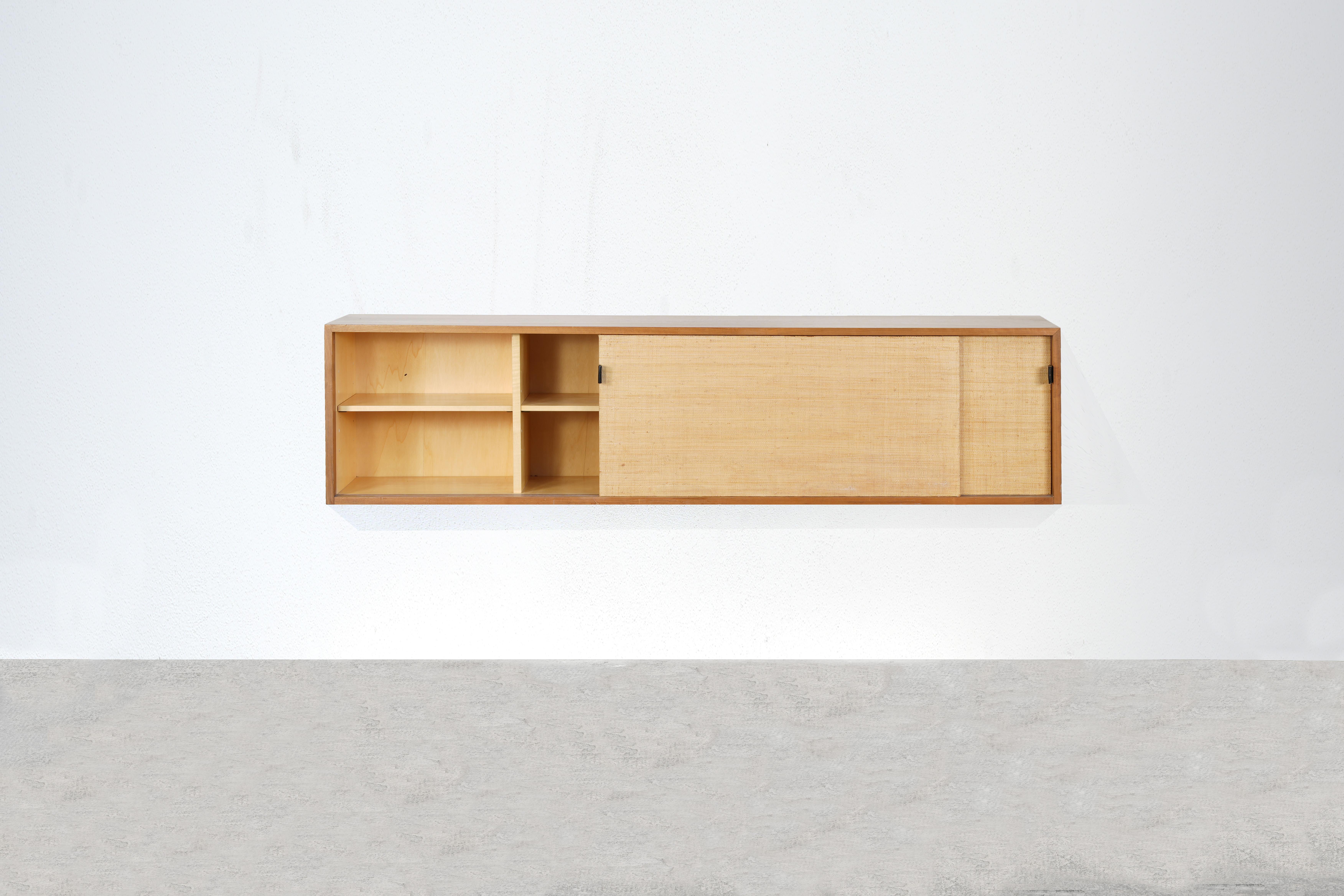 Very rare and beautiful wall-mounted sideboard designed by Florence Knoll for Knoll International in the 1950s.
The wallboard is made of nut wood and seagrass and is still in very good original condition with just little traces of usage.