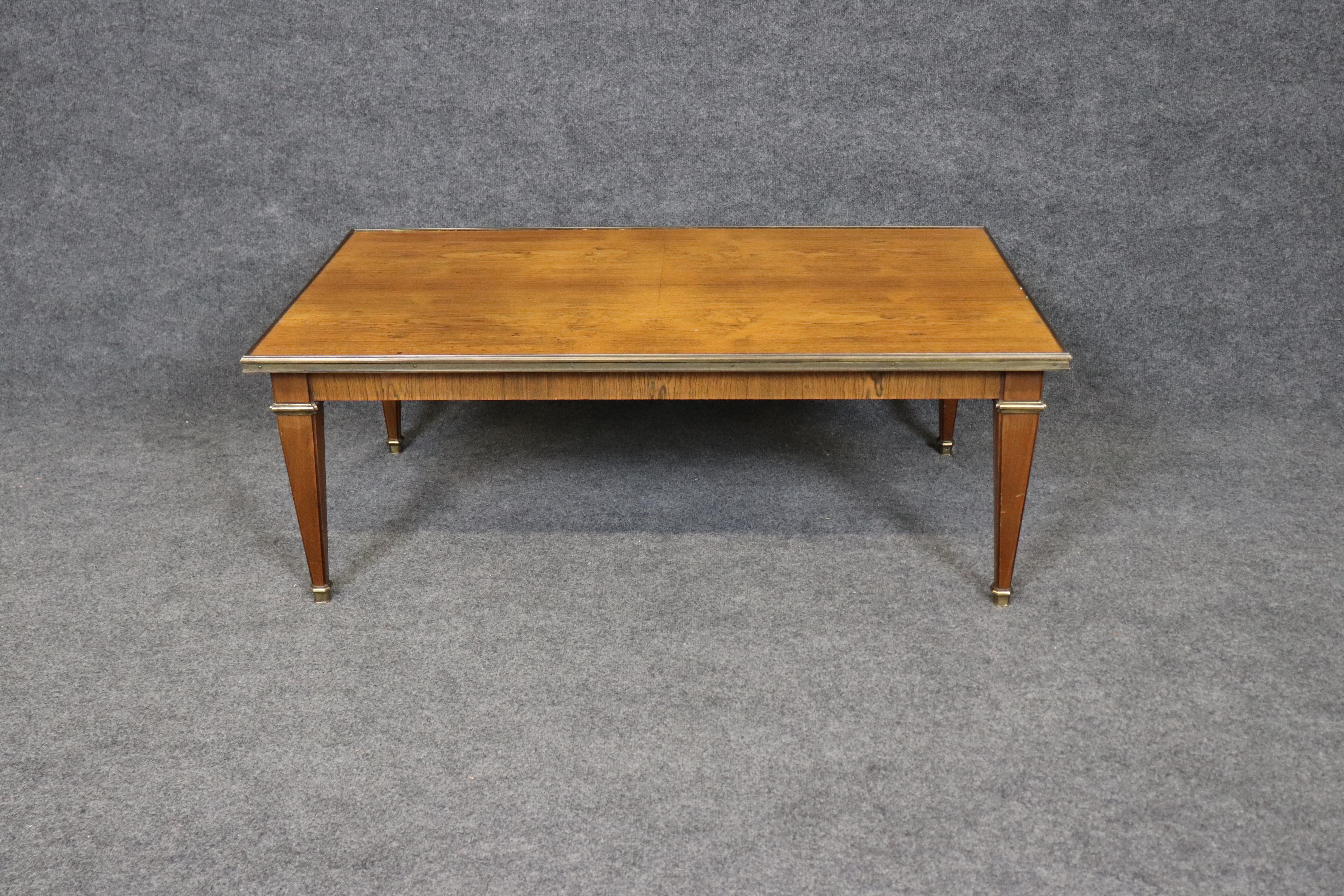 This is a gorgeous Baker Furniture Directoire style coffee table with brass mounts. The table is in its original condition and features Baker quality and superb brass and wood quality. The table is in good condition with minor signs of age and use.