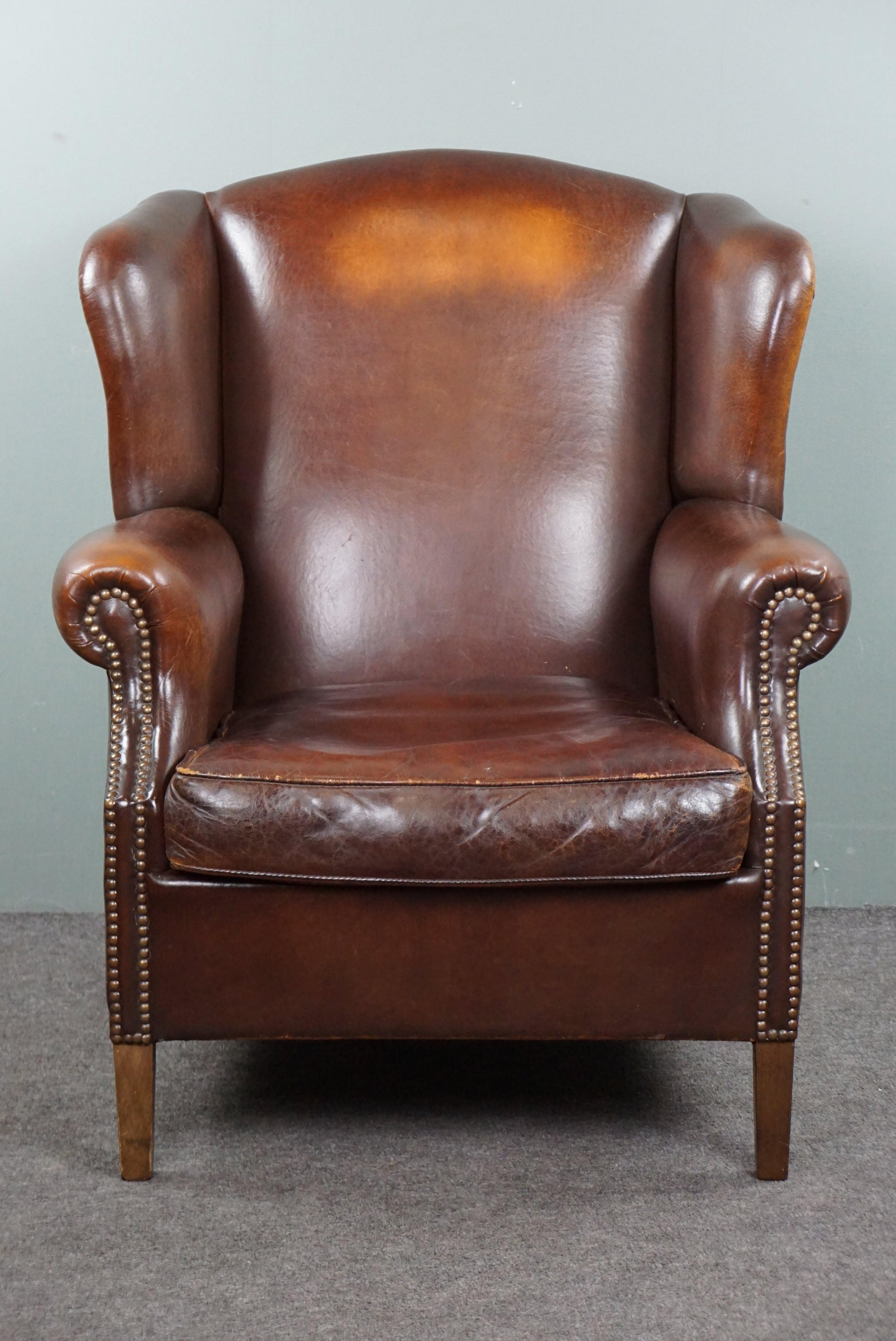 Offered is this beautiful sheep leather wing chair finished with beautiful decorative nails.

This pearl has a beautiful warm color and a beautiful patina.
Anyone who takes this unique eye-catcher into their home is assured of a wonderfully seated