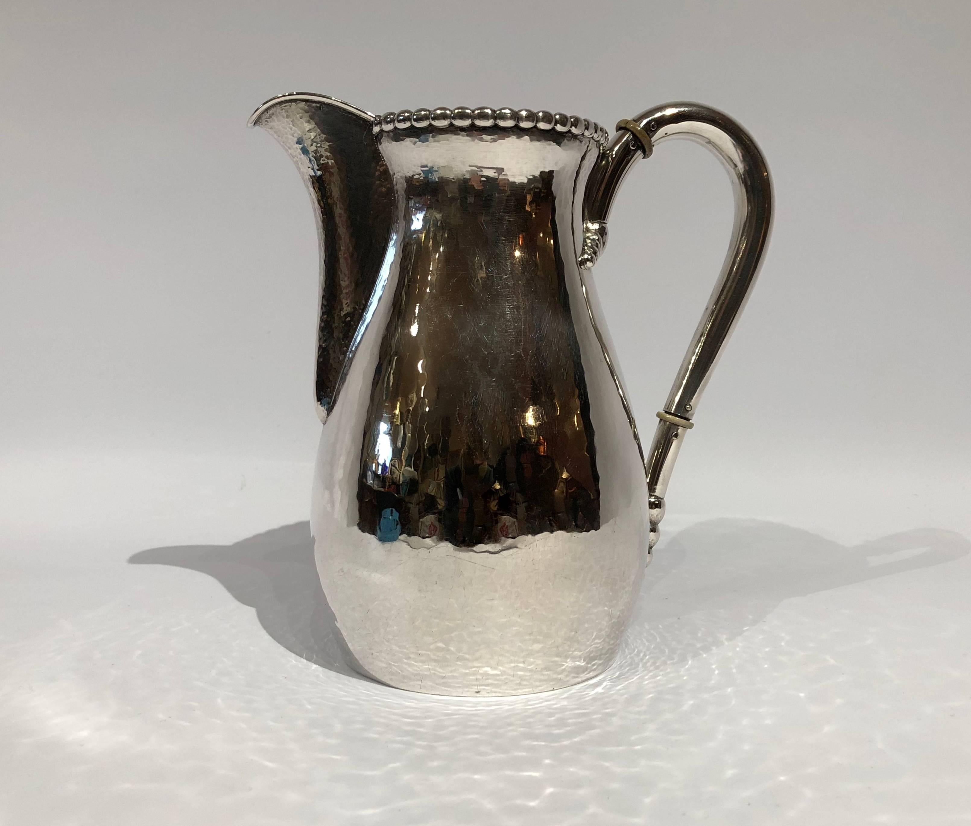 Beautiful water jug in hammered hallmarked silver and simple pearl edge.