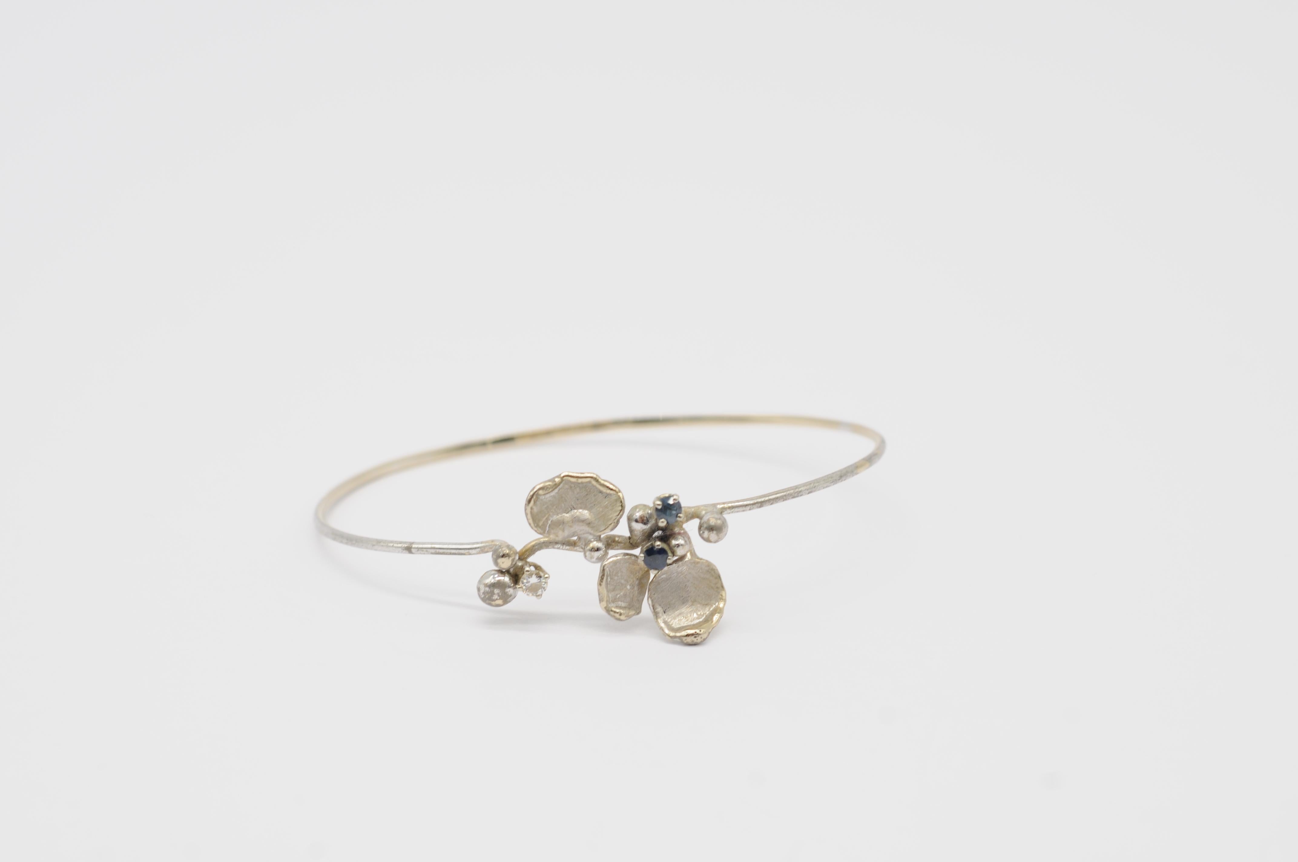 Élevez votre style avec l'envoûtant bracelet en or blanc Whiting en or 18k. Ce charmant et exquis bracelet présente un seul diamant et deux saphirs, chacun méticuleusement taillé de façon brillante. Témoignage du savoir-faire de la forge allemande