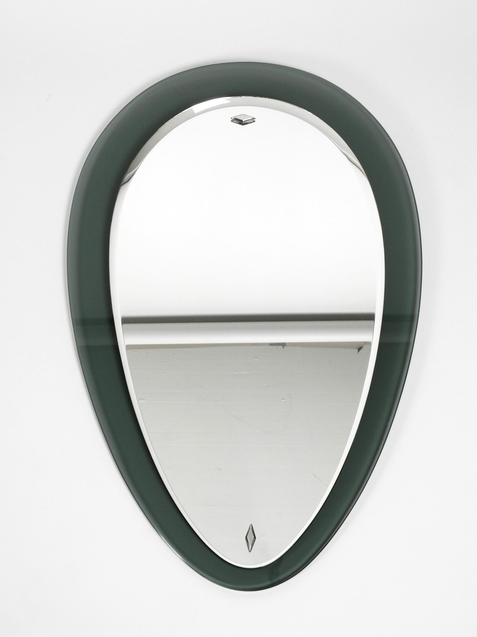 Beautiful large heavy midcentury double glass wall mirror.
Manufactured by Fontana Arte. Made in Italy.
Great design in the shape of a drop of water.
Very high quality and solid construction.
The mirror glass is screwed to the green transparent