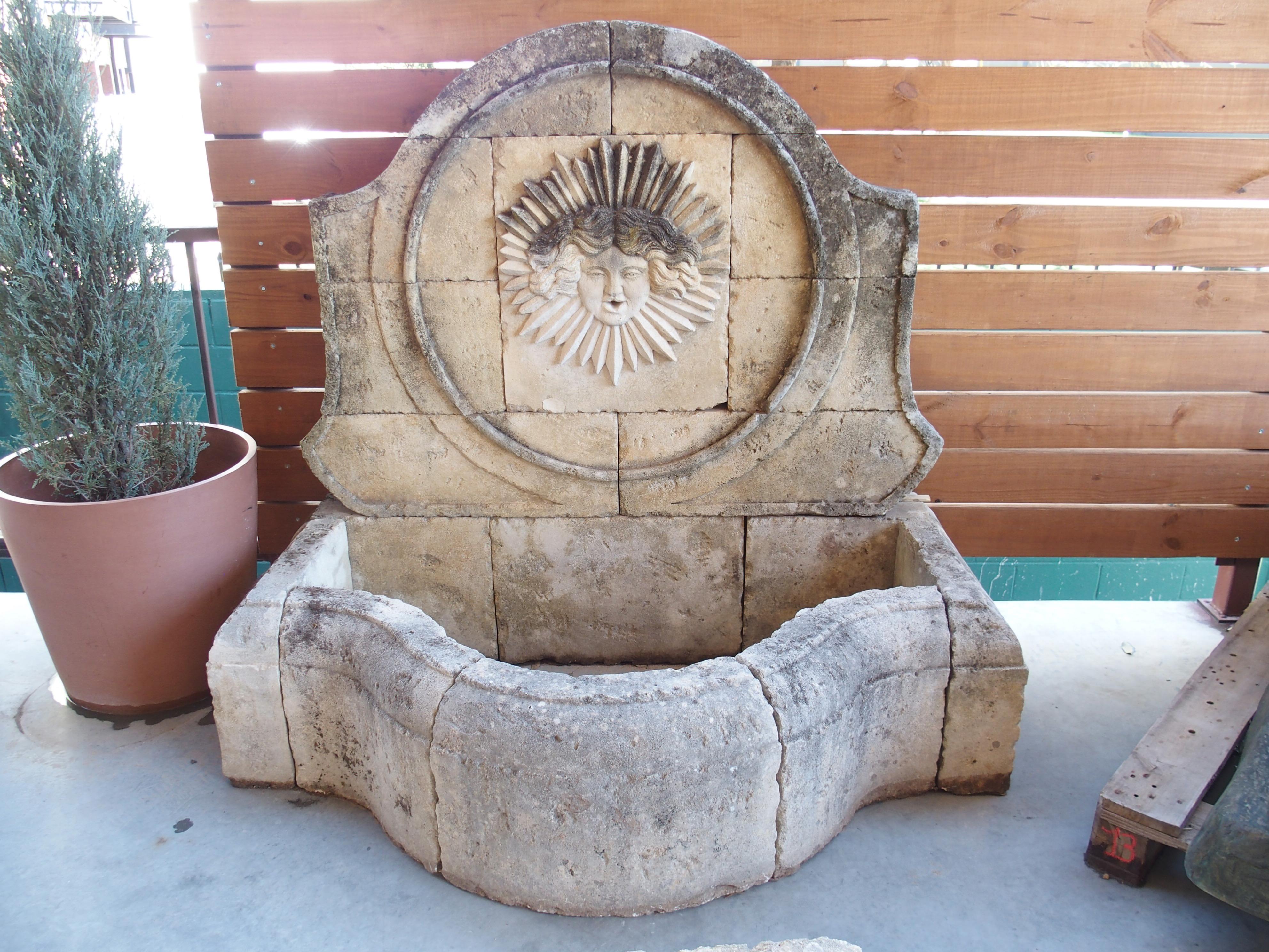 The immaculate hand-carved details of this French sunburst wall fountain are enhanced by the beautiful patina of the aged limestone. 17 pieces of limestone were carved for the fountain, including eight for the shapely en chapeau basin. The curves of