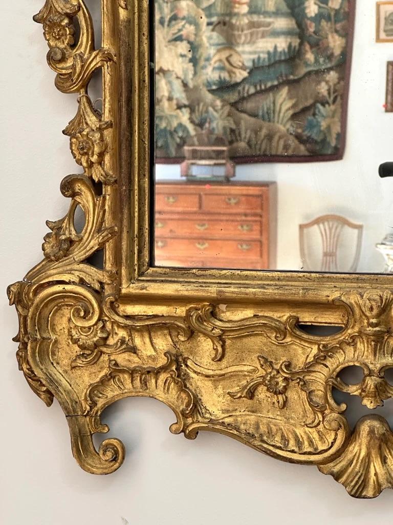 Beautifully carved, gilded 18th Century Mirror, likely French, with gilded surface, scrolled ears, carved shells and rosettes. Has an old Christie’s label dating piece 1783-1790. 

39”H x 27”W

