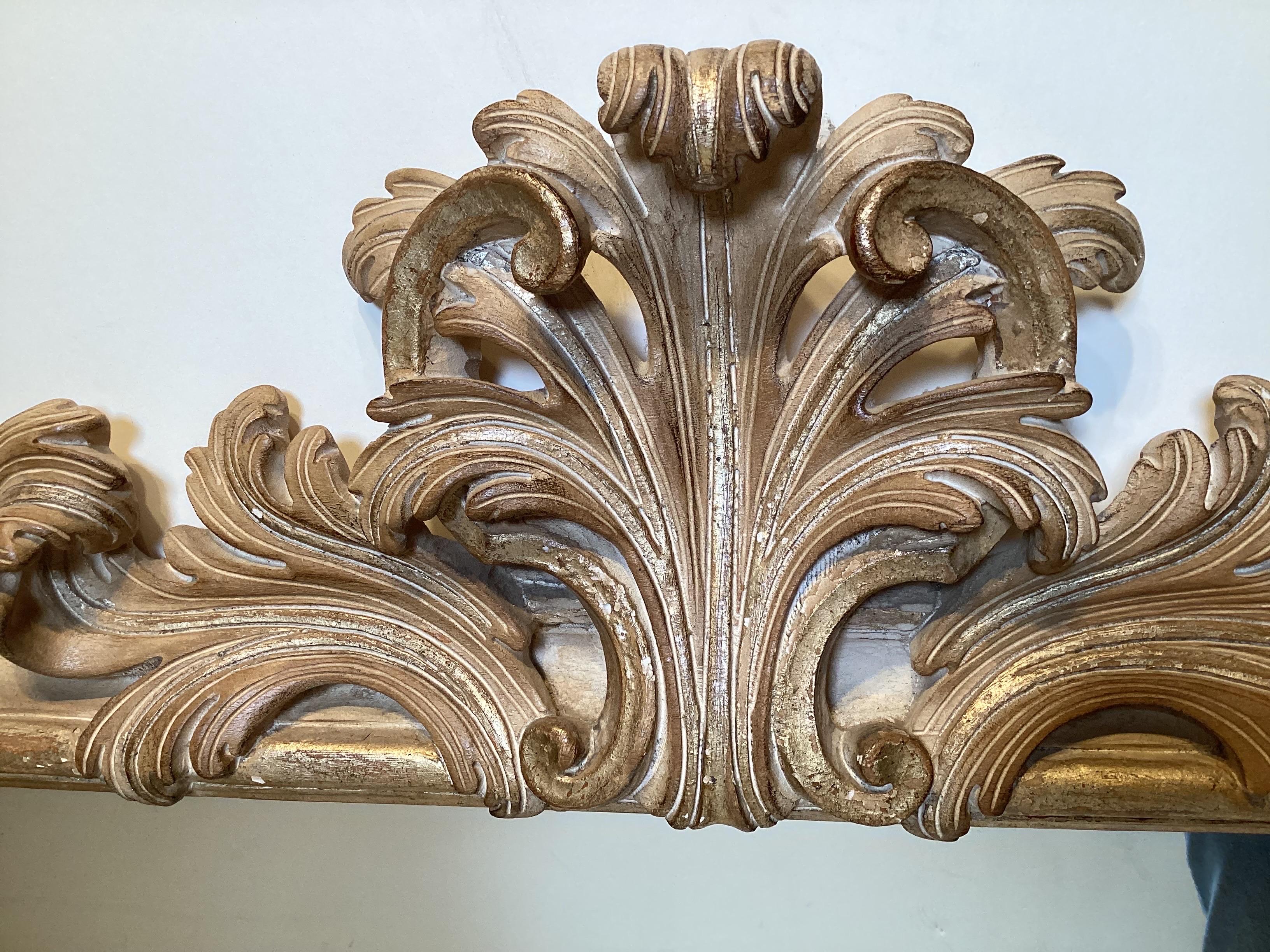 Hand carved Rococo style wood mirror. The wood frame with a light wash of gilding with mostly wood showing through. The plume top with scrolling at the corners in a thick detailed frame.