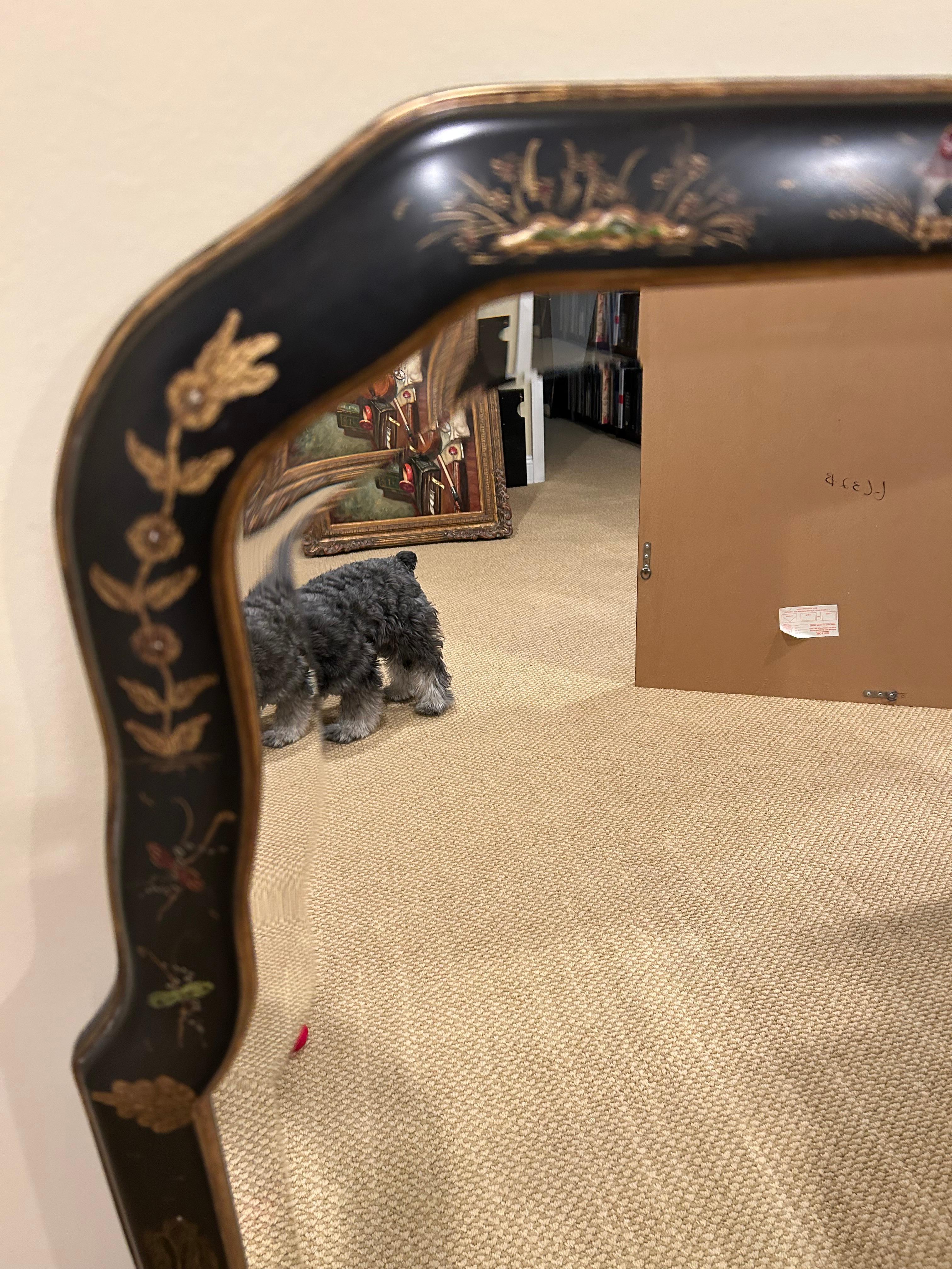 Elegant large black Chinoiserie mirror having curved top, bevelled mirror, and lovely Asian motif painted decorations in gold with touches of red and green.
