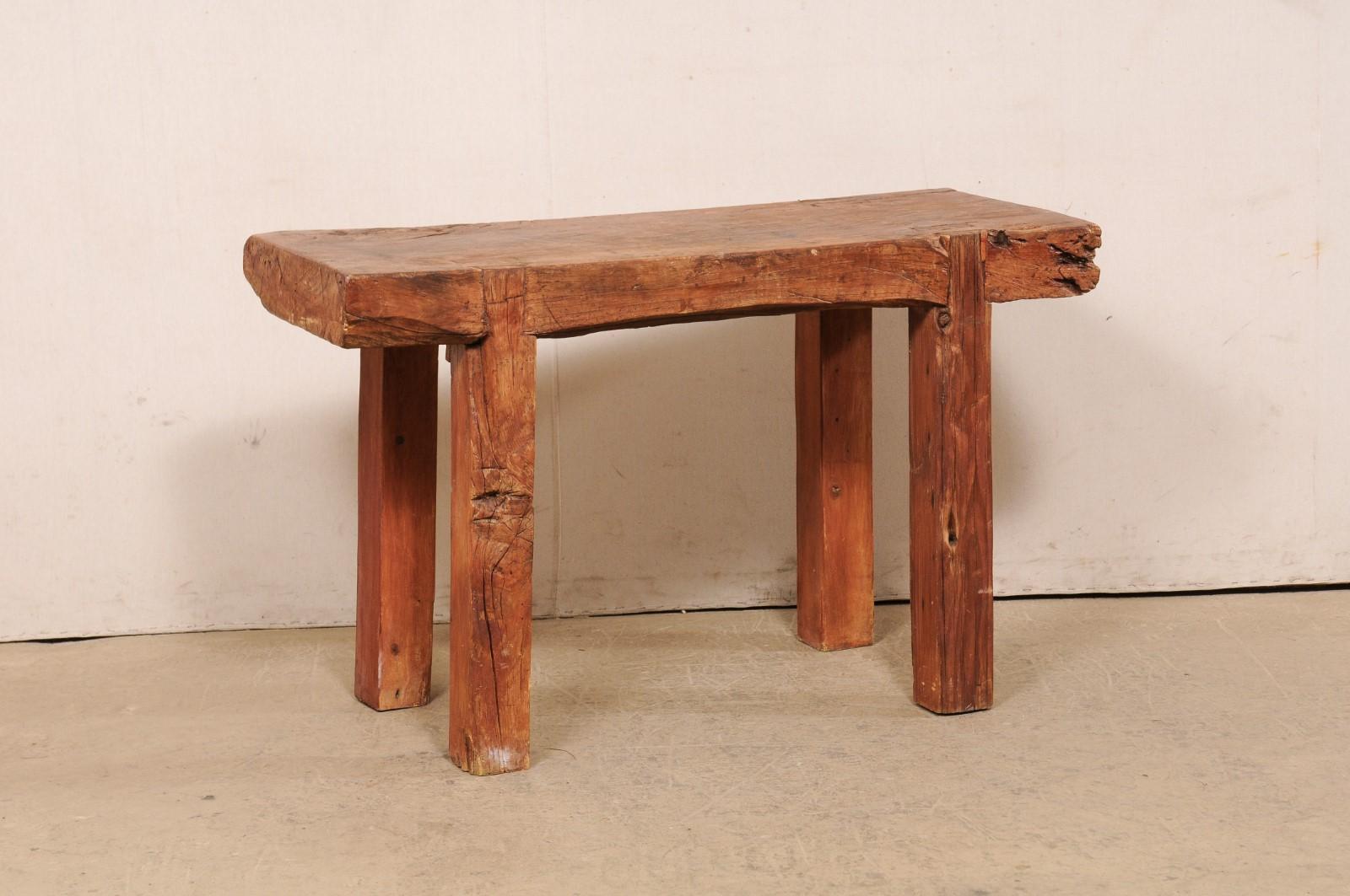 A vintage chopping-block style table from Asia. This rustic table features a thick single, rectangular-shaped slab/chopping block top, which is raised on four, thickly squared legs. The wood has a lovely areas of natural knots, an aged patina