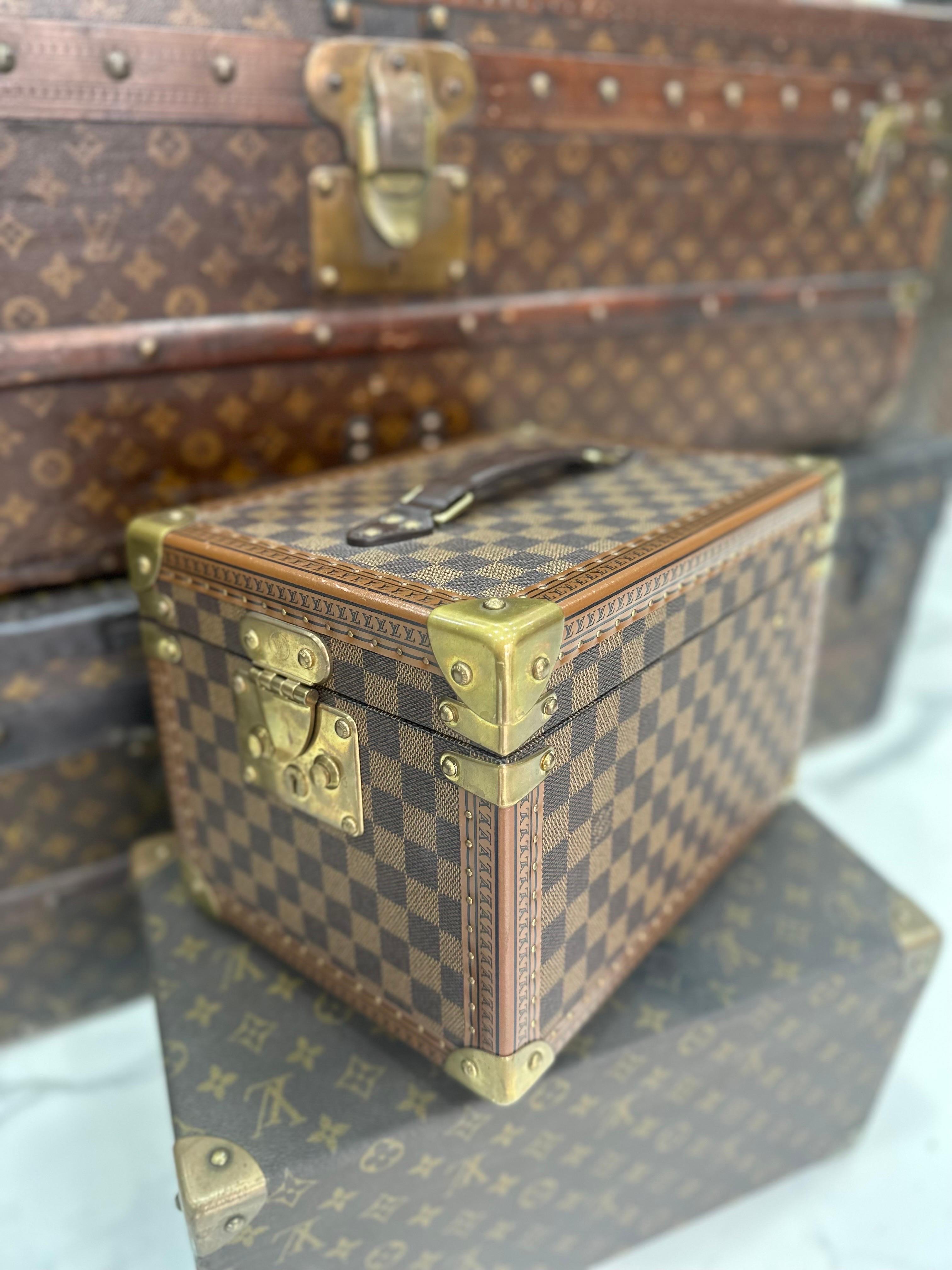 Beauty firmato Louis Vuitton, modello rigido realizzati in tela damier ebene con inserti in pelle marrone e hardware dorati. Dotato di una chiusura con incastro, internamente rivestita in alcantara rosso, abbastanza capiente. Munito di un manico