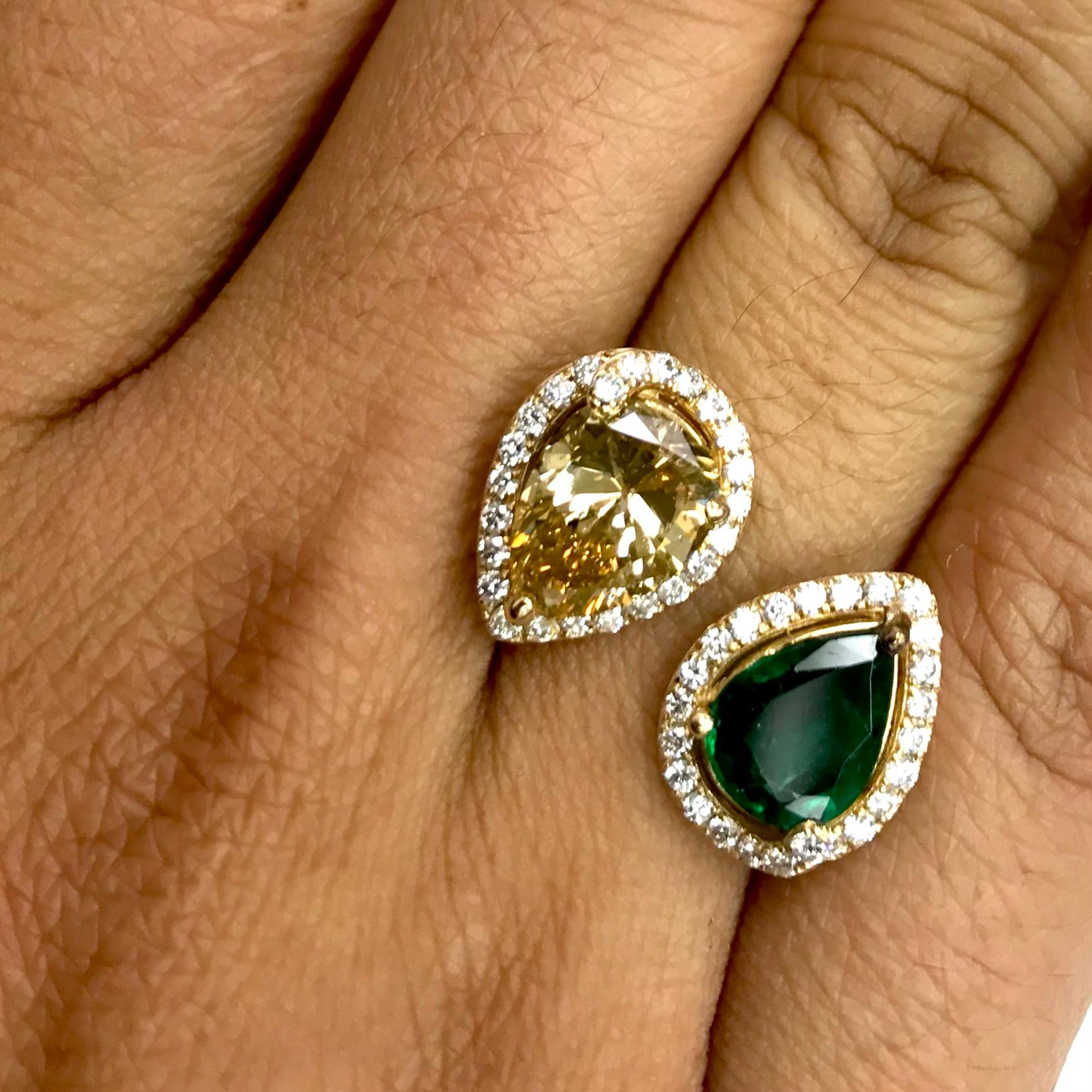 This Diamond & Green Emerald Ring features a Diamond & an Emerald Pear Shape pointing in opposite directions designed to float over ones fingers. The white diamond halo highlights the color and accentuates by contrasting the center gemstones.