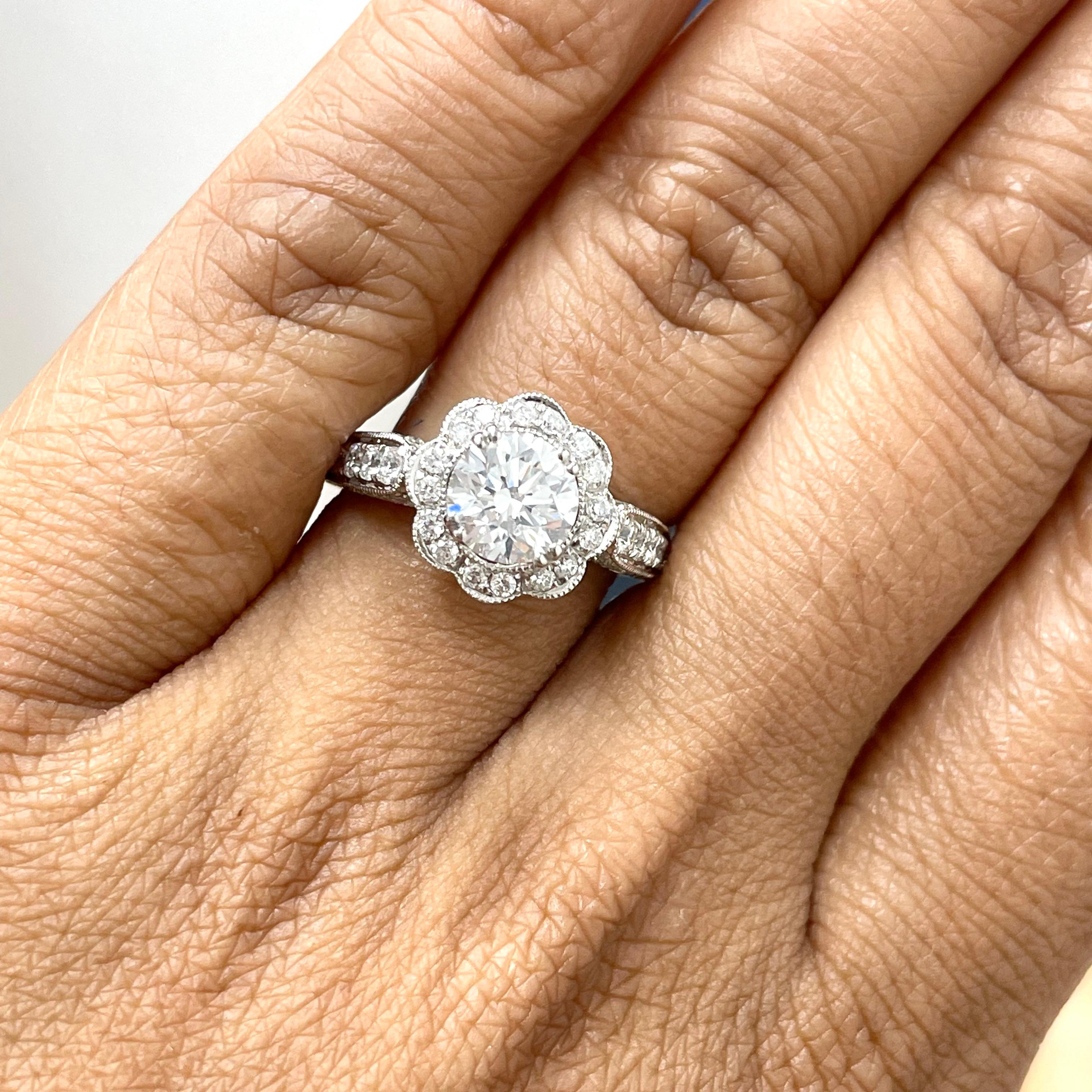 A flower shaped halo surrounds the solitaire with leaf like details on the basket. This inspired solitaire diamond engagement is floral and earthy in nature.

Center Diamond Shape: Round
Center Diamond Weight: 1.21 cts 
Diamond Color: G
Diamond