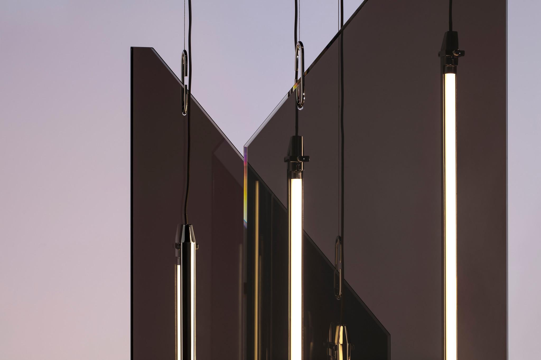 The Resolute Flags fixture is two layers of angular two way mirror glass forms are suspended from the ceiling, incorporating linear led profiles wrapped in polished nickel. Flags thus creates a geometric interplay of form, intersecting layers of