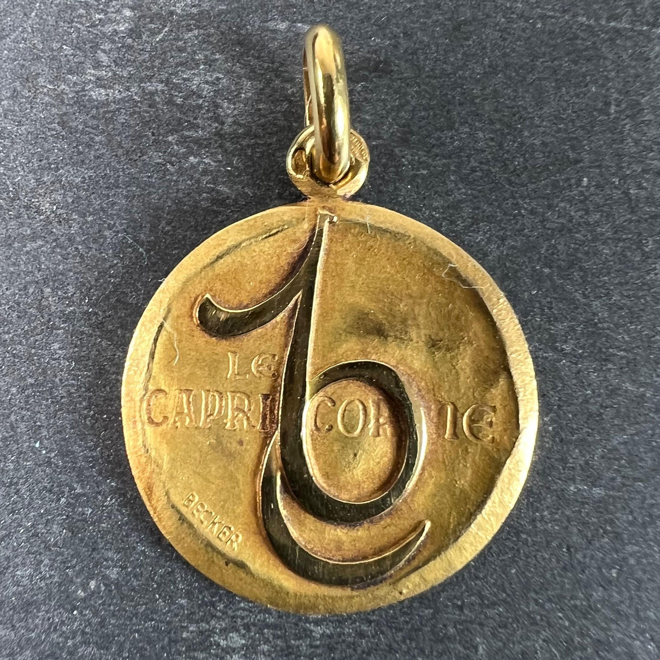 A French 18 karat (18K) yellow gold charm pendant depicting the Zodiac star-sign of Capricorn as the astrological symbol for the sign in polished gold on a matt gold convex recessed base, with the phrase 'Le Capricorne' beneath. Signed Becker and