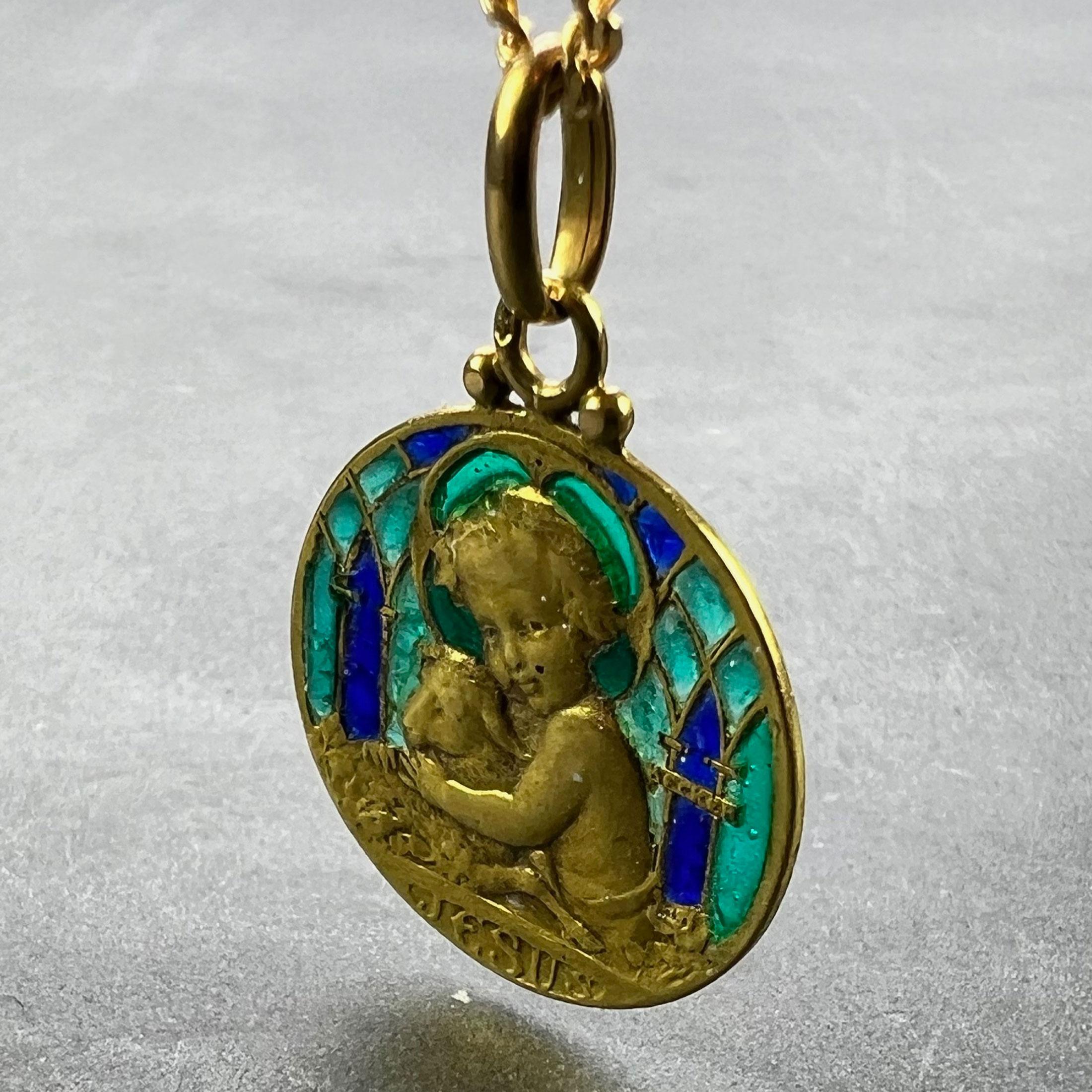 Ciondolo charme francese in oro giallo 18 carati (18K) disegnato come una medaglia rotonda raffigurante Gesù Bambino con un agnello che rappresenta l'Agnello di Dio, con contorno di smalto blu e verde plique a jour disegnato come finestre di chiesa