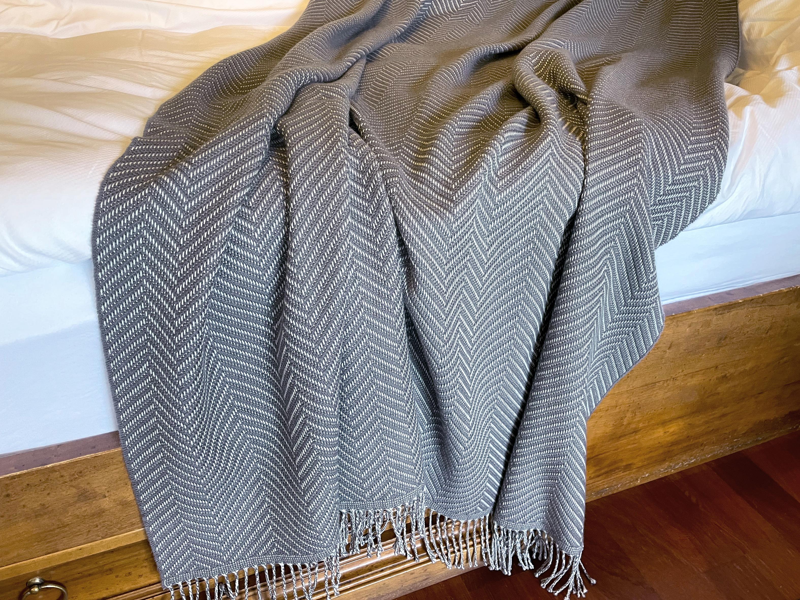 Entworfen in Berlin von Catharina Mende, gewebt aus 100% extrafeiner Merino in Schottland: Dieser exquisite Bettüberwurf in der Farbe Grau, gewebt in Schottland aus feinster extrafeiner Merino, ist ein Stück Schönheit und Eleganz für jedes