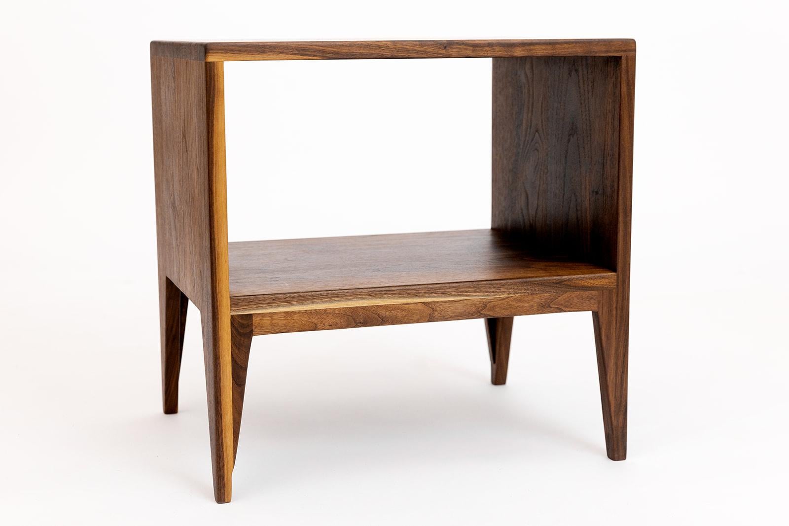 La table de chevet est dotée de pieds effilés et d'une étagère. Il mesure 20