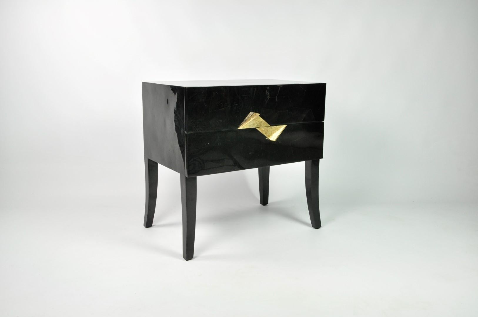 This rectangular bedside table has two drawers and it is made of a black shell marquetry.
The handles are in casted brass.
The interior has a dark wood veneer.
There are 4 feet in black shell with a curved design.

 
The dimensions of this