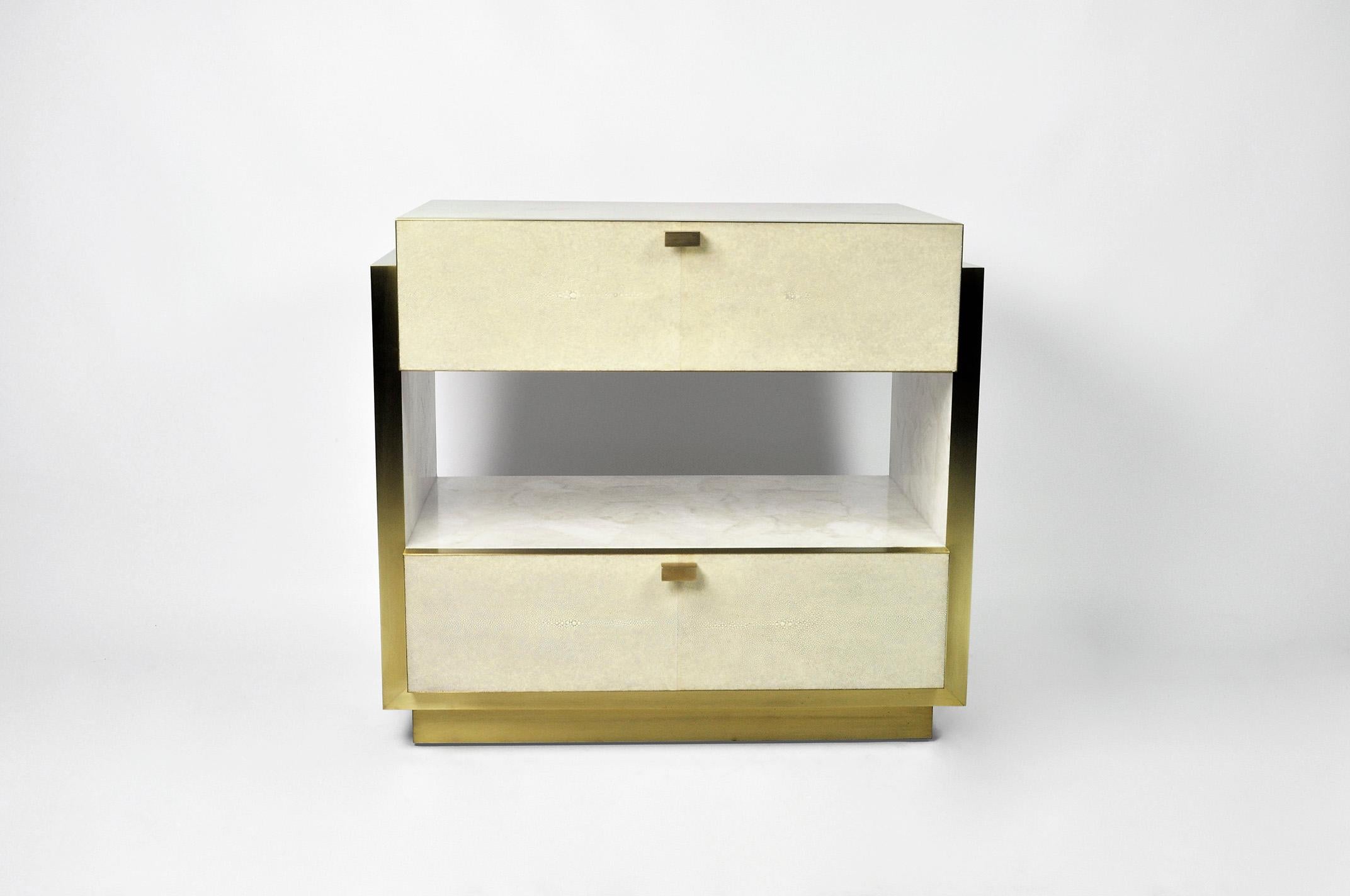 This rectangular bedside table has two drawers and it is made of white rock crystal marquetry with shagreen drawers.
The edges and the base have brass trims.
The handles are in brass.

The dimensions of this piece are W23.6