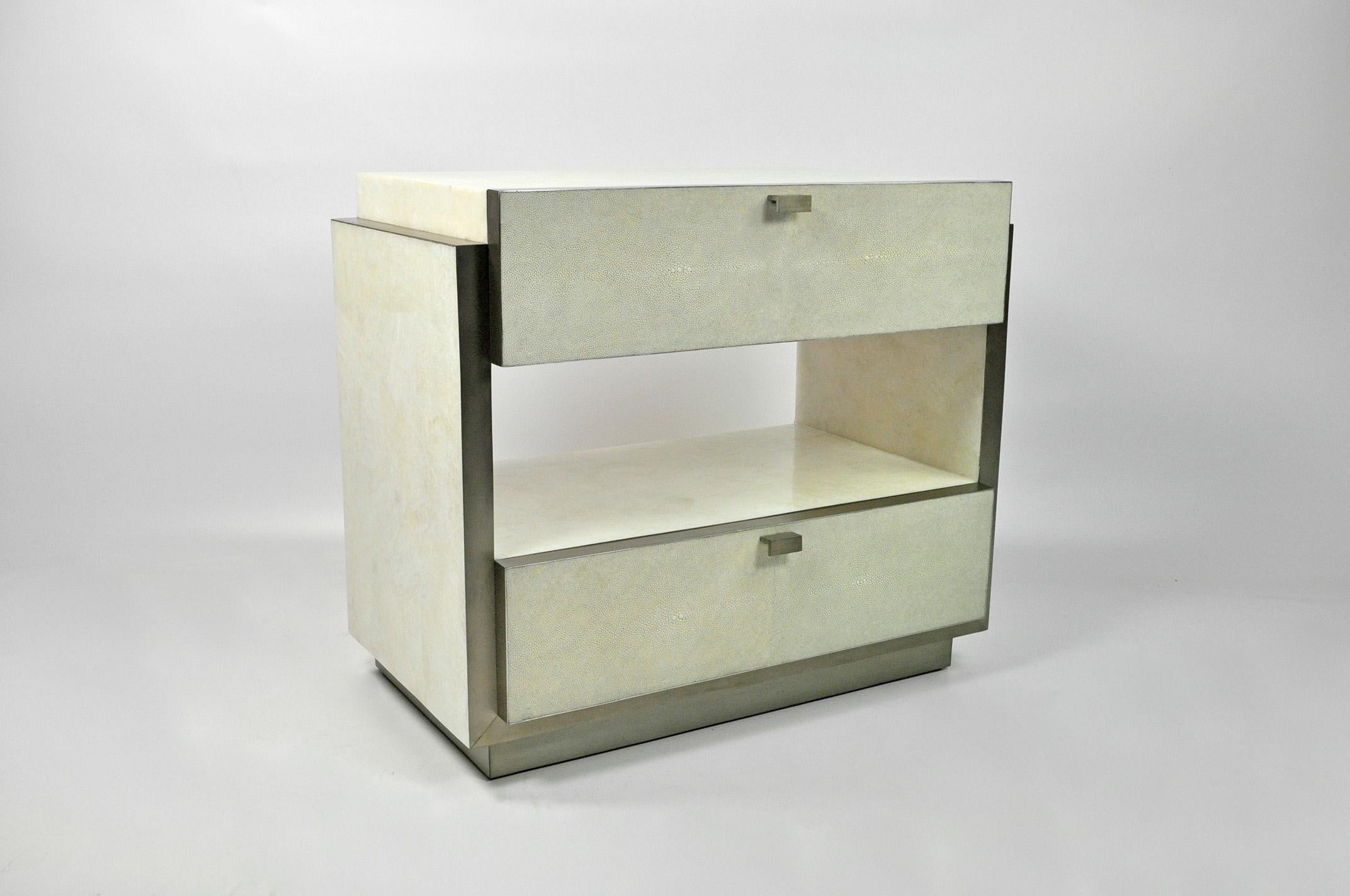 This rectangular bedside table has two drawers and it is made of white rock crystal marquetry with shagreen drawers.
The edges and the base have brushed stainless steel trims.
The handles are in stainless steel.

The dimensions of this piece are