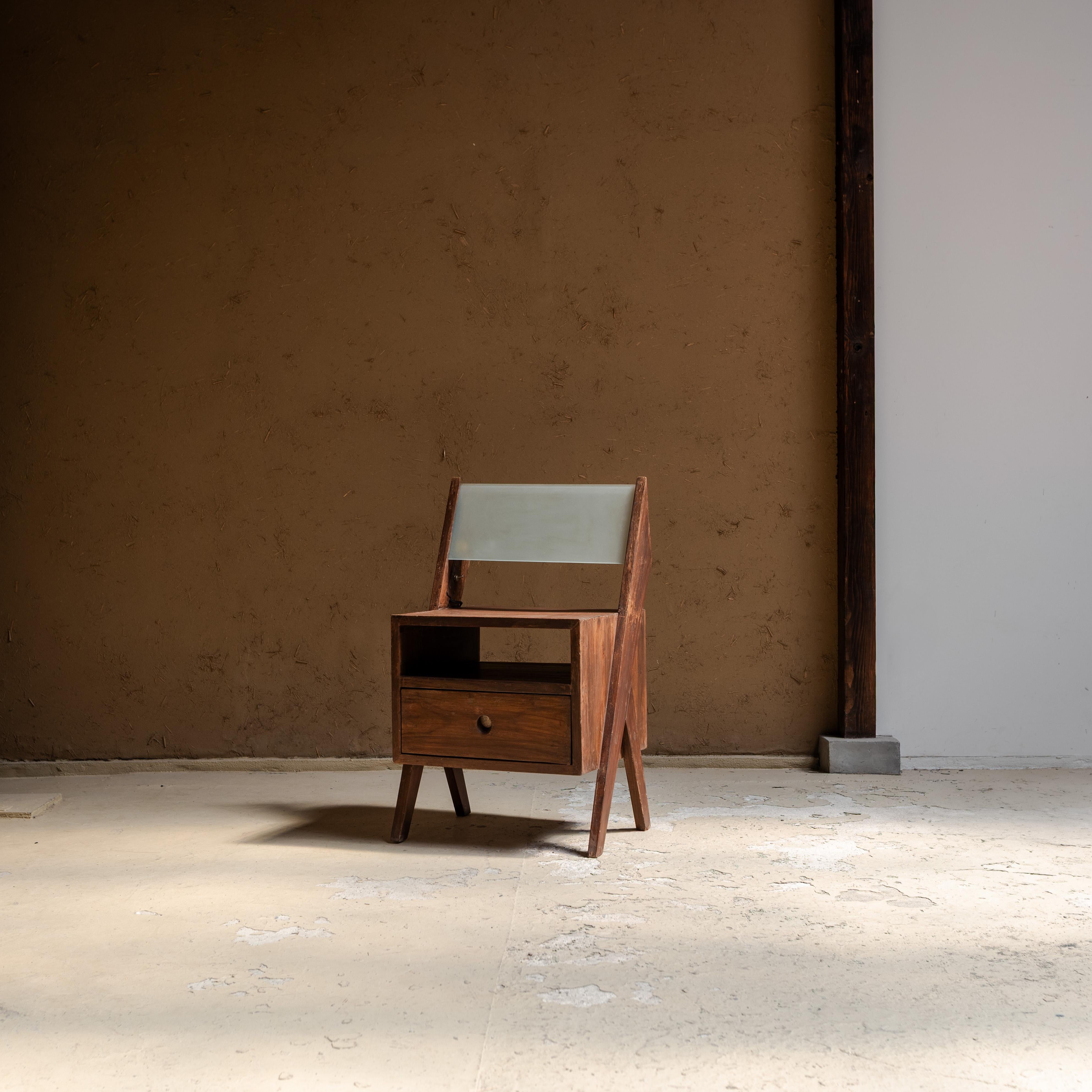 This bedside table with integrated lamp is an exceptional piece designed by Pierre Jeanneret for the Chandigarh project in India. 

Crafted from solid teakwood, it features Jeanneret’s signature “V” shaped legs, a minimal open shelf, a small drawer