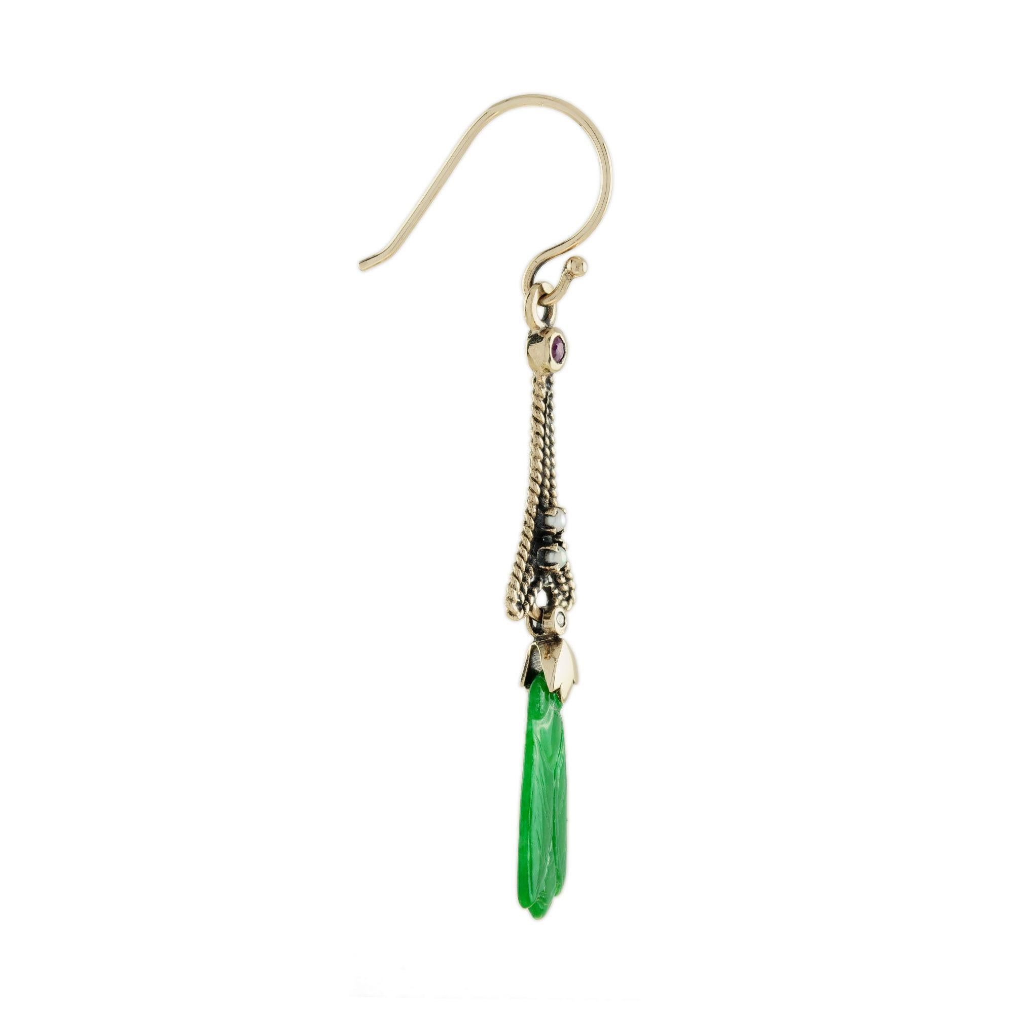 The natural jade in these lovely earrings has some very special shape. Both pieces have a strong green color and well bee carvings. The jade is suspended in a 9k yellow gold setting with pearl, diamond, and ruby geometric link on the top. The