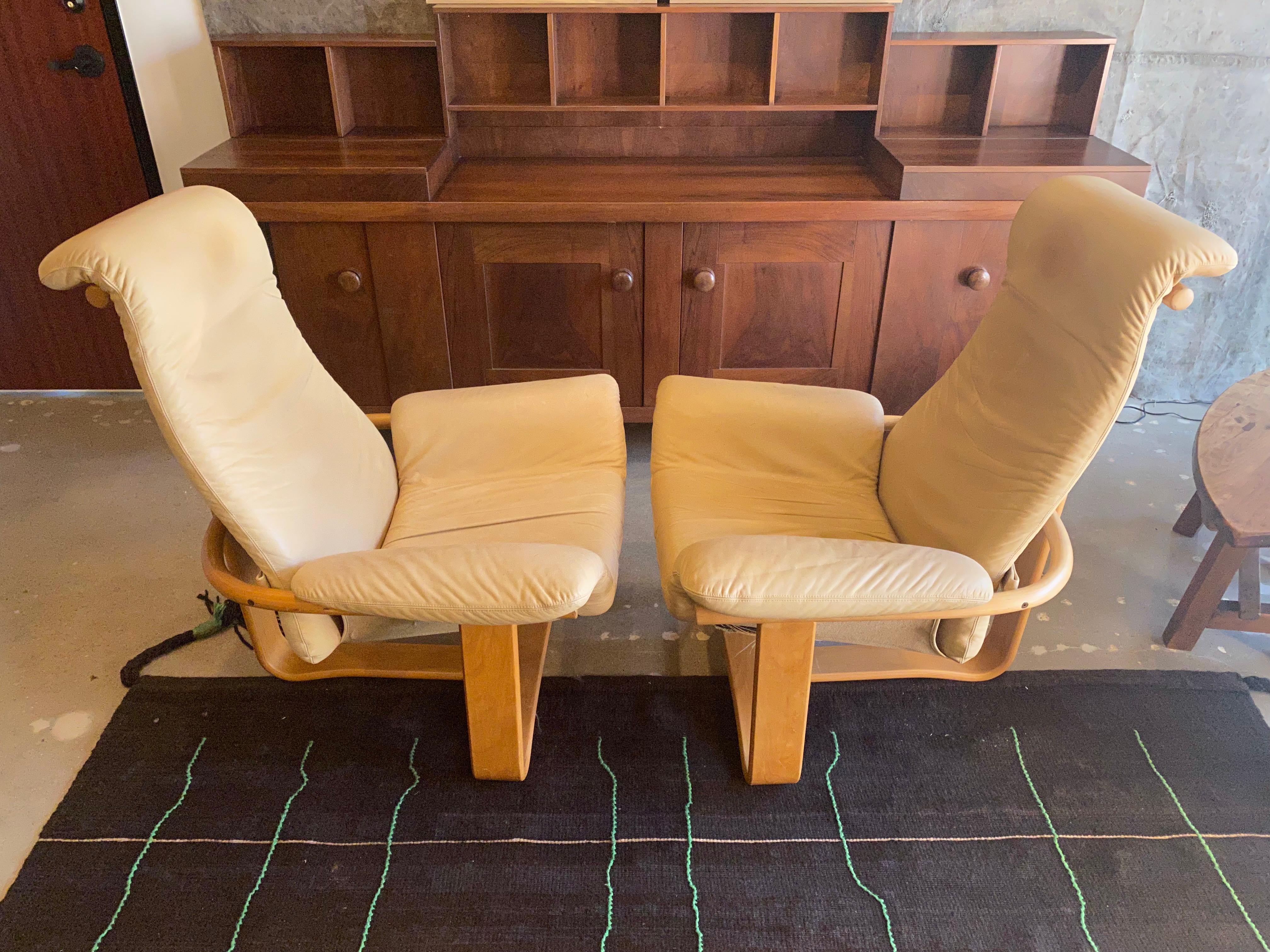 Pair of high style Scandinavian modern lounge chairs with beech wood frames and buff leather (aniline dyed) cushions. A uniquely sculptural pair of mid-century modern seats that are as comfortable as they are stylish.  