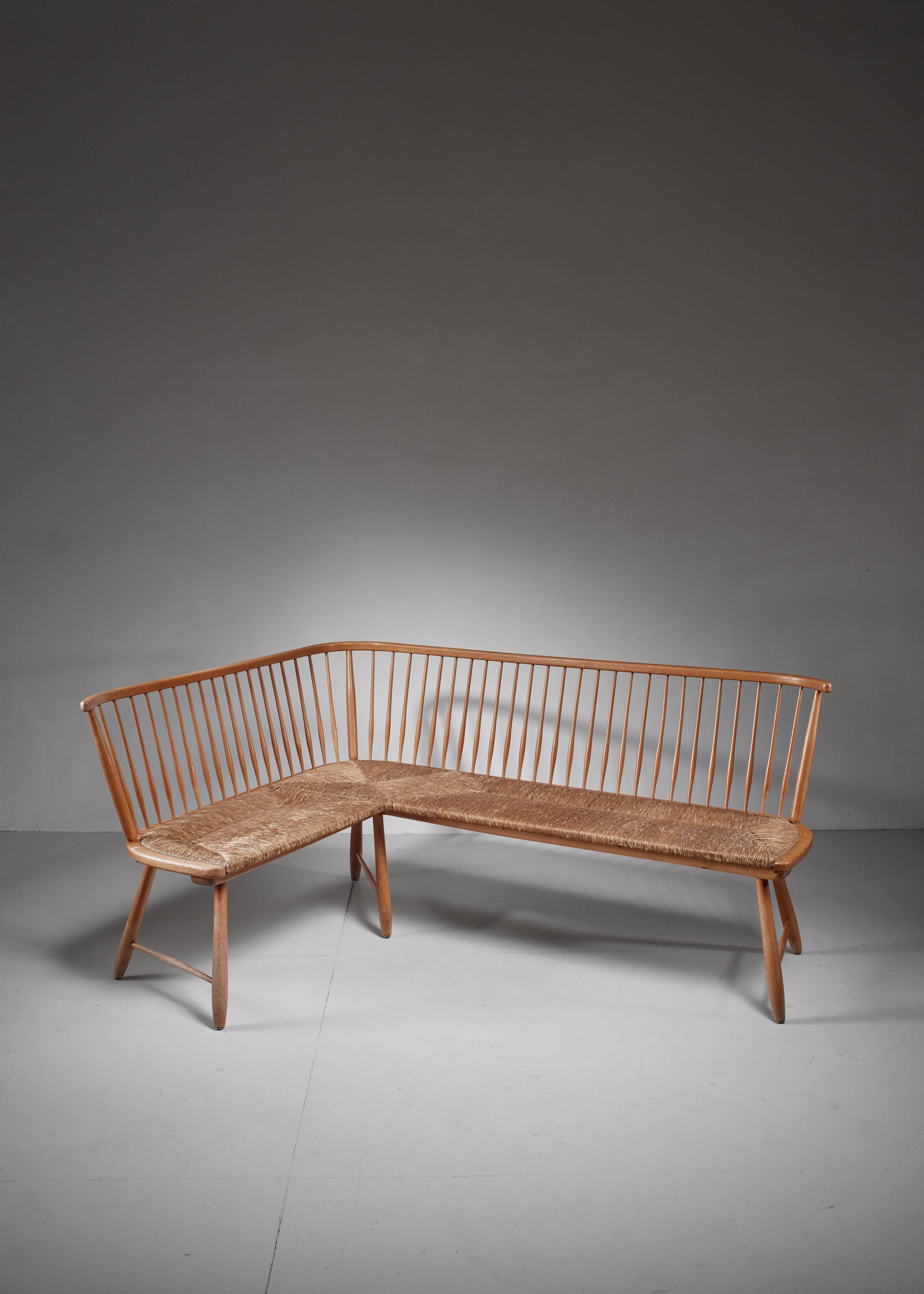 A midcentury corner bench by German architect Arno Lambrecht. The sofa is made of beech with a spindle backrest and a woven cane seating in a perfect condition.

Its simplicity and honest elegance combines with midcentury and Scandinavian modern.