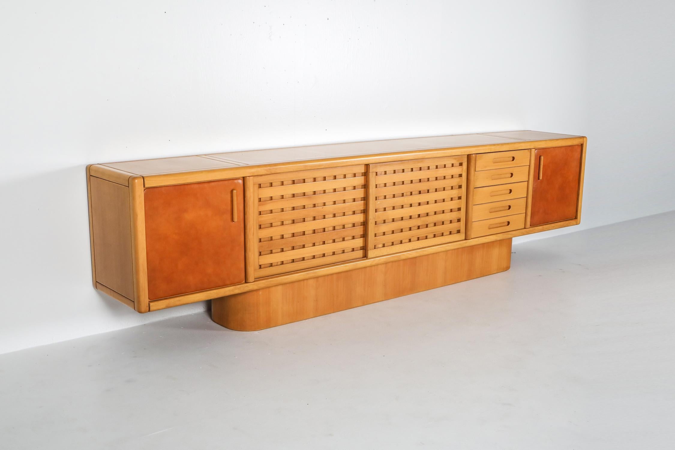 Mario Marenco credenza, Postmodern, beech, tan leather, Italy, 1970s

Impressive and large piece made in solid walnut.
The two exterior doors have a tan / cognac leather upholstery.
The two middle grid shaped doors are sliding both sides,