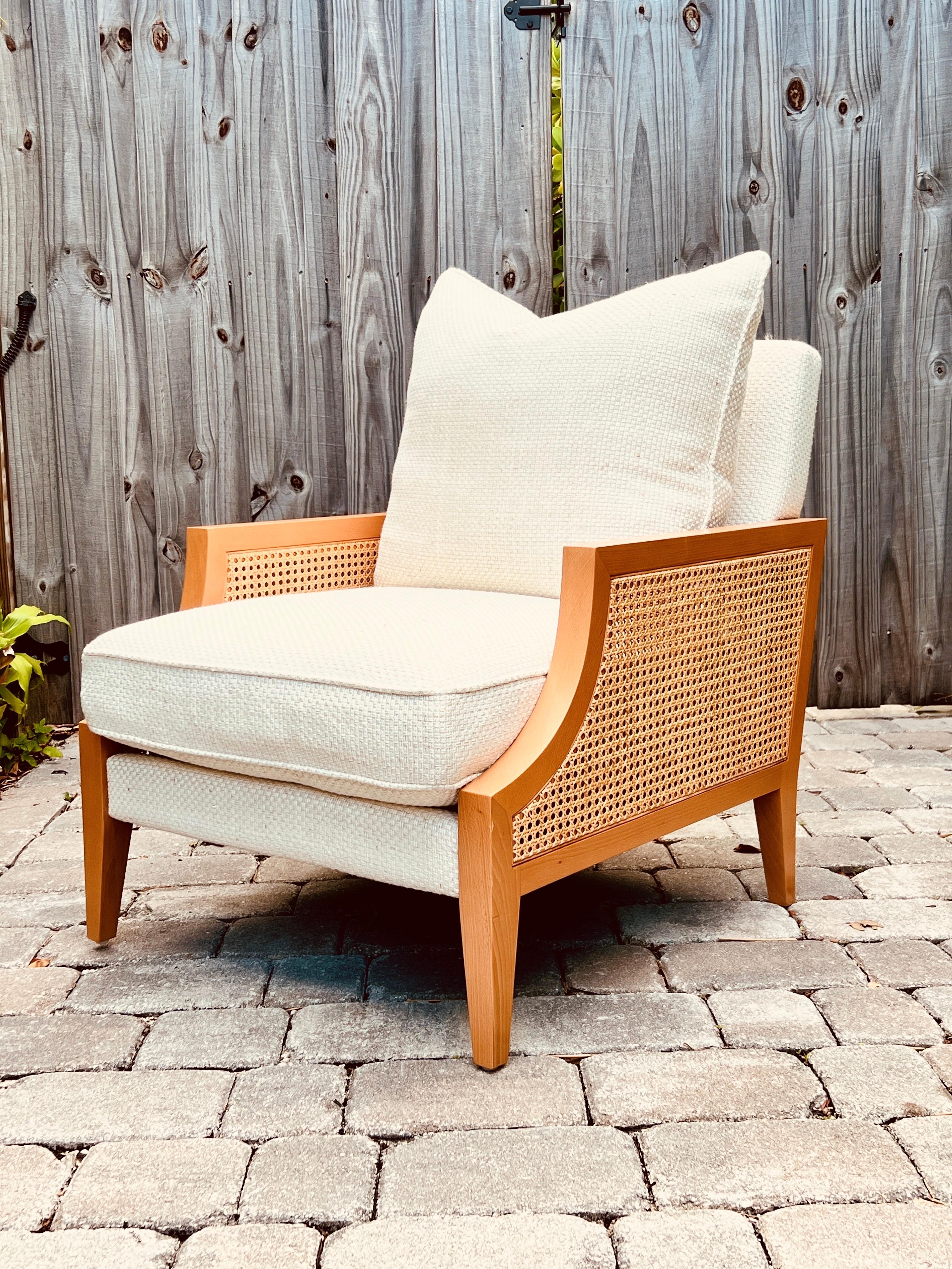 The Axel Armchair by La Maison Pierre Frey, features a sleek contemporary solid beech wood frame with cane sides in a natural tan finish. Newly upholstered in Pierre Frey fabric from the Hanoi Collection, which features a basketweave design in hues