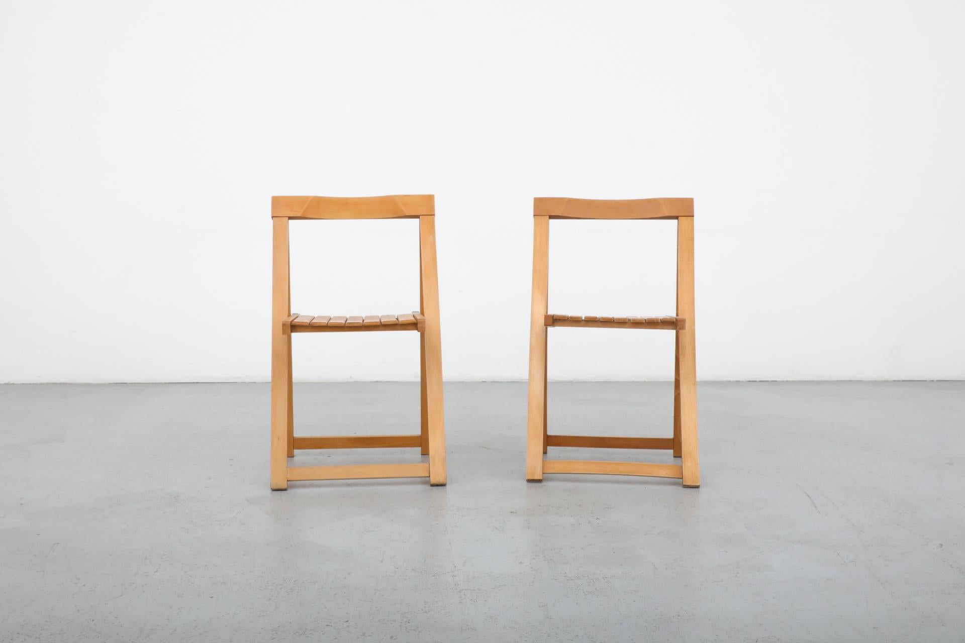 Sillas plegables Aldo Jacober para Alberto Bazzani, 1960. Sillas plegables de madera de haya clara con funcionalidad para ahorrar espacio y estilo de mediados de siglo. Plegadas miden 18 x 1,625 x 34,875. En estado original con desgaste visible. Una