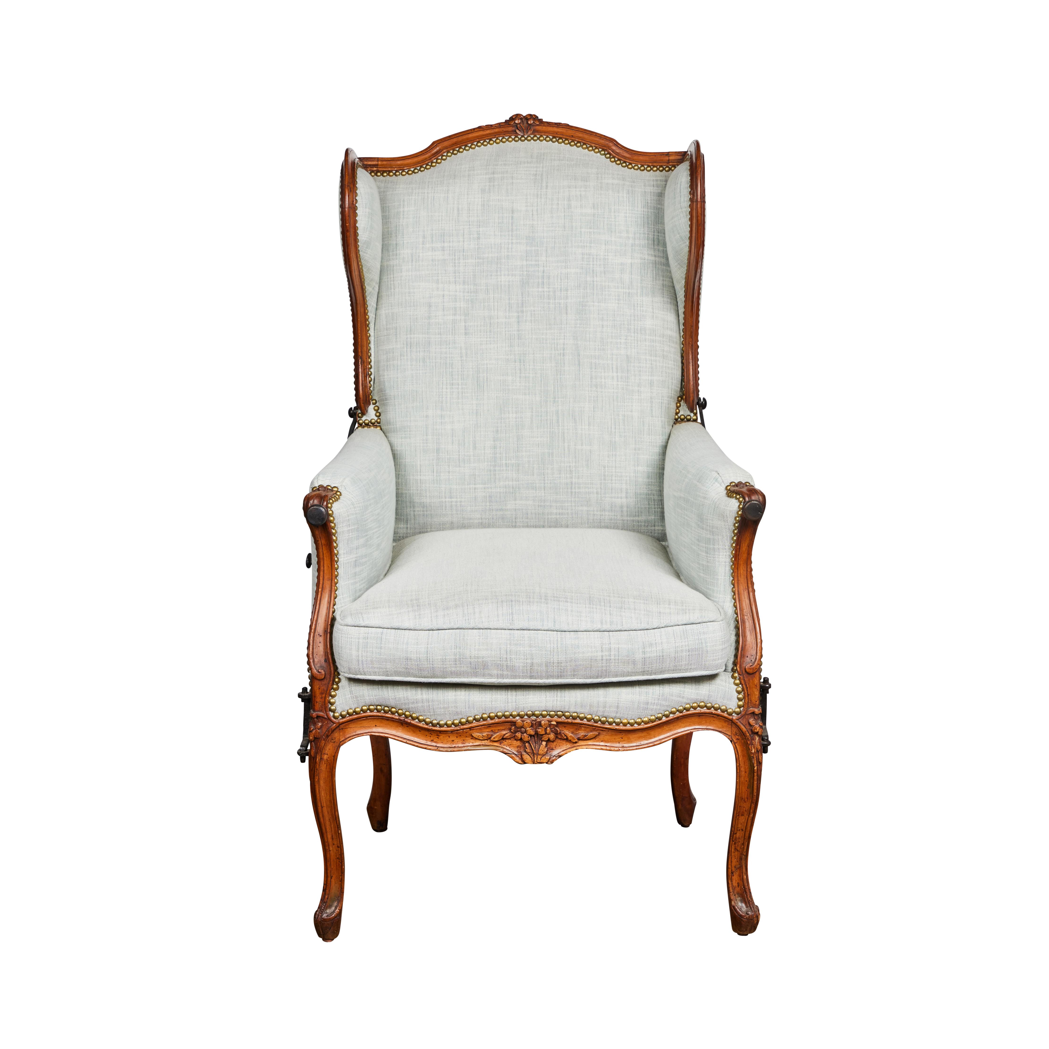 Hand carved Beechwood, winged back, reclining ratchet chair with original iron mounts. Newly upholstered in woven fabric.  