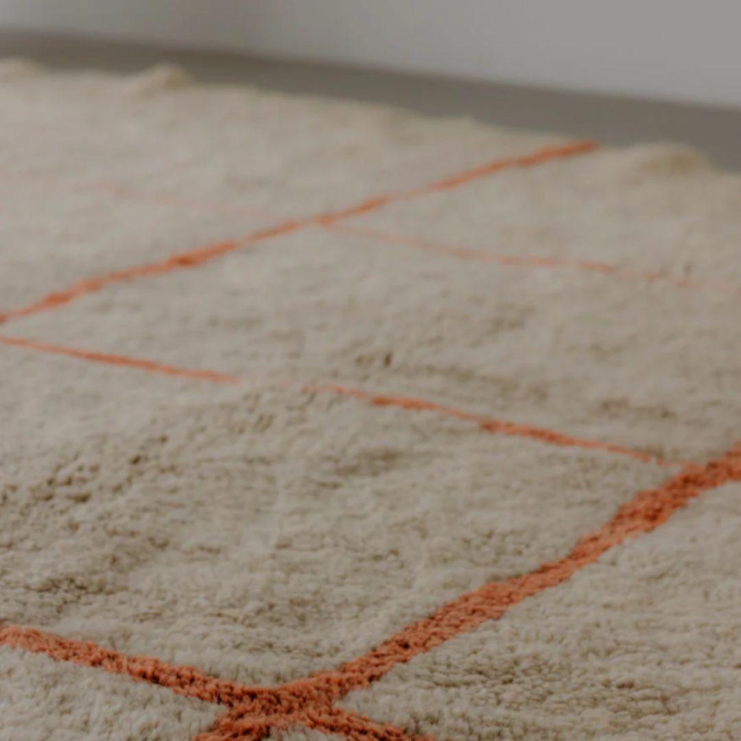 Ein großer ovaler Berberteppich in warmen Farbtönen ist wirklich bemerkenswert. Der neutrale Sockel schafft einen beruhigenden Hintergrund, während die tiefen Terrakotta-Linien einen auffallenden visuellen Reichtum hinzufügen. 

Die ovale Form des